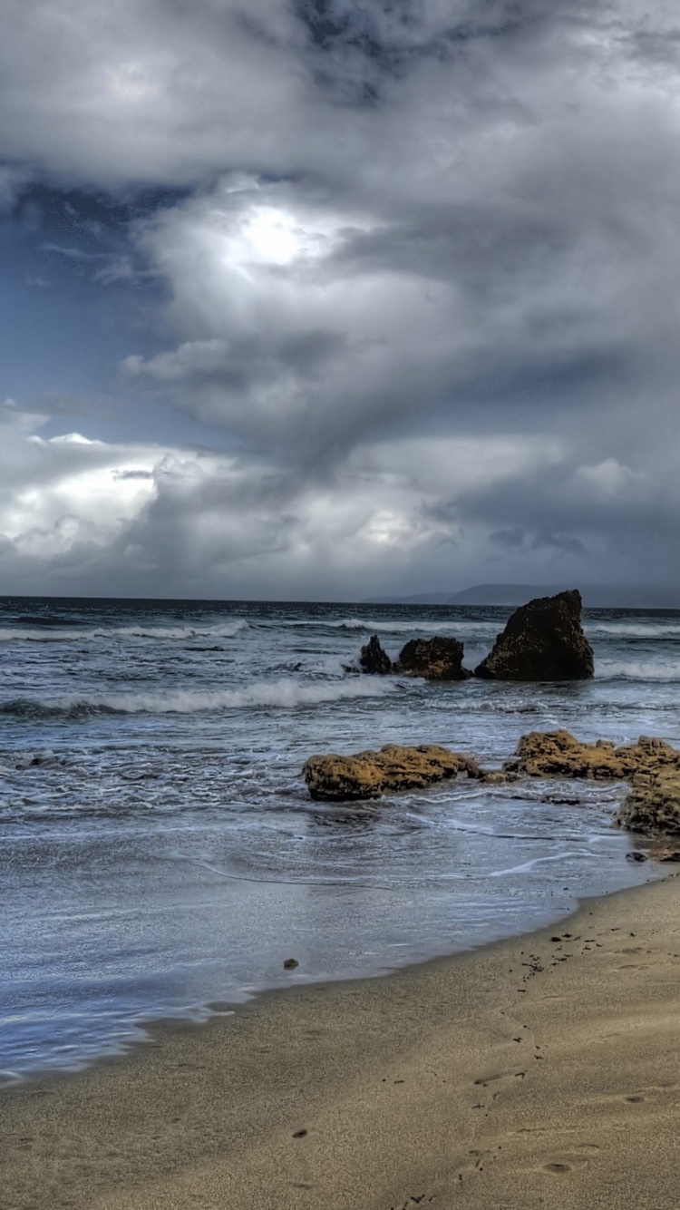 Formation de Roche Brune Sur le Bord de Mer Sous Les Nuages Blancs et le Ciel Bleu Pendant la Journée. Wallpaper in 750x1334 Resolution