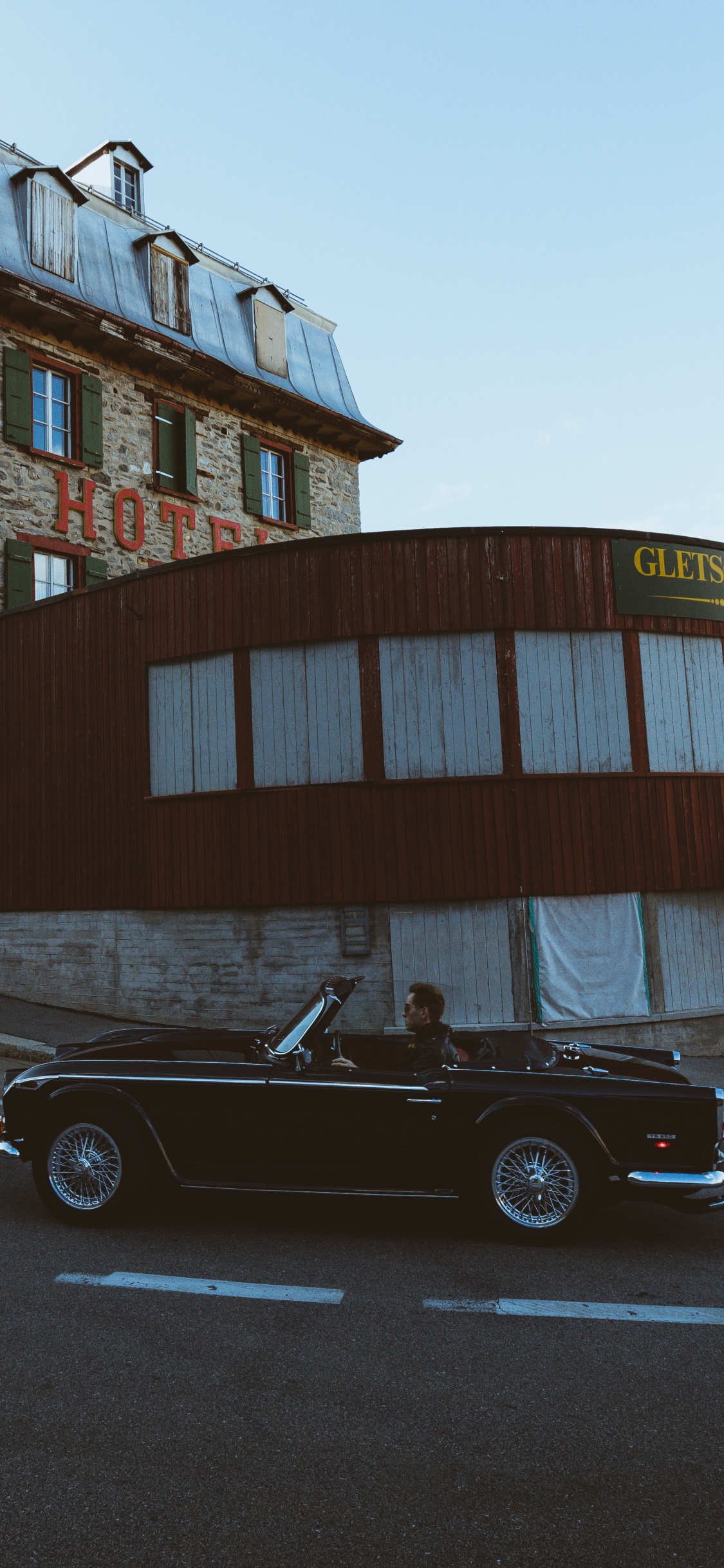 Black Coupe Parked Beside Brown Concrete Building During Daytime. Wallpaper in 1125x2436 Resolution