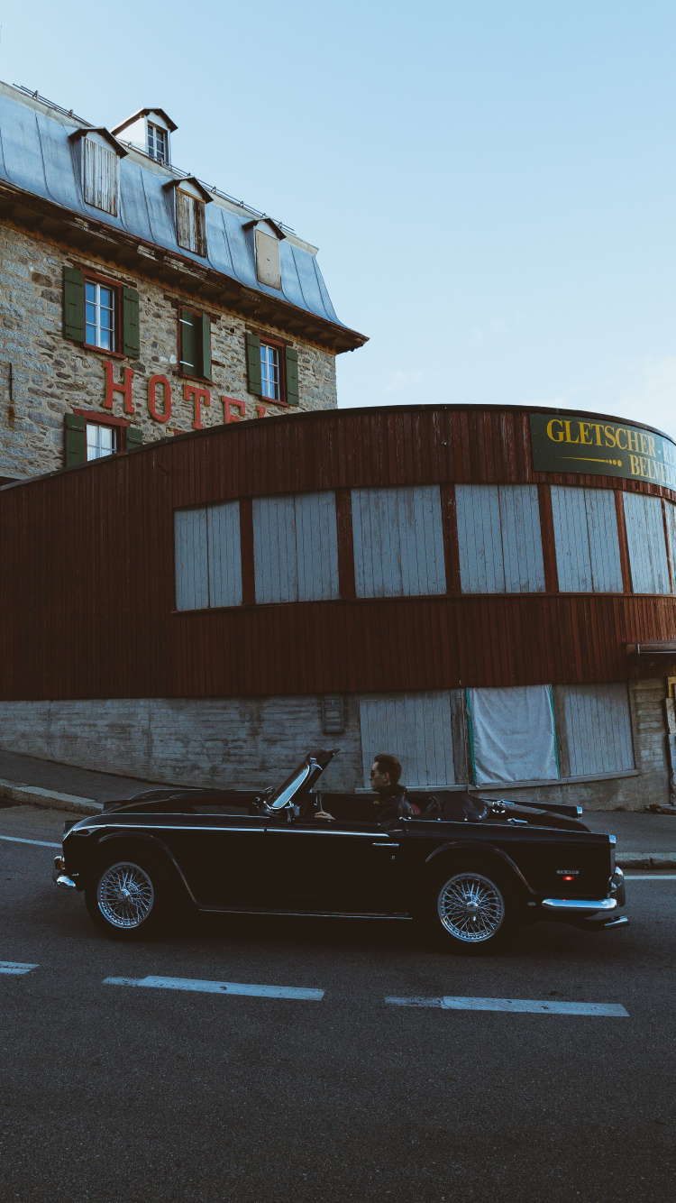 Black Coupe Parked Beside Brown Concrete Building During Daytime. Wallpaper in 750x1334 Resolution