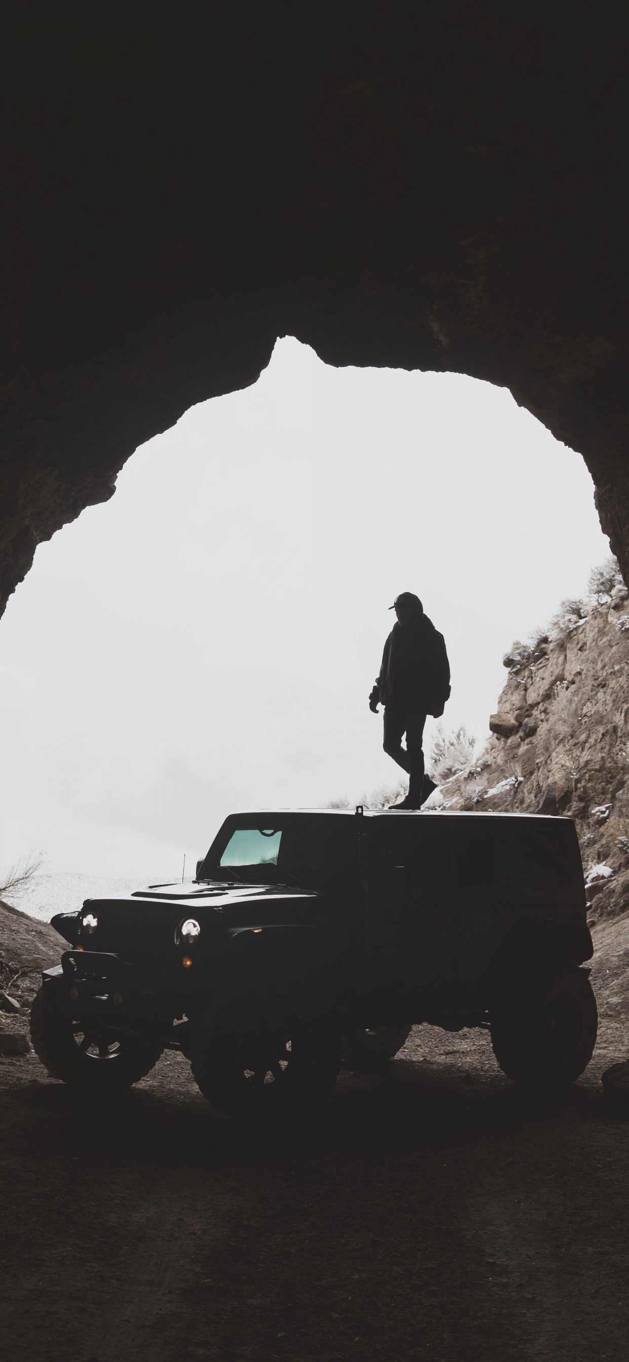 Homme en Veste Noire Debout Sur Une Jeep Wrangler Noire à L'intérieur de la Grotte Pendant la Journée. Wallpaper in 1242x2688 Resolution