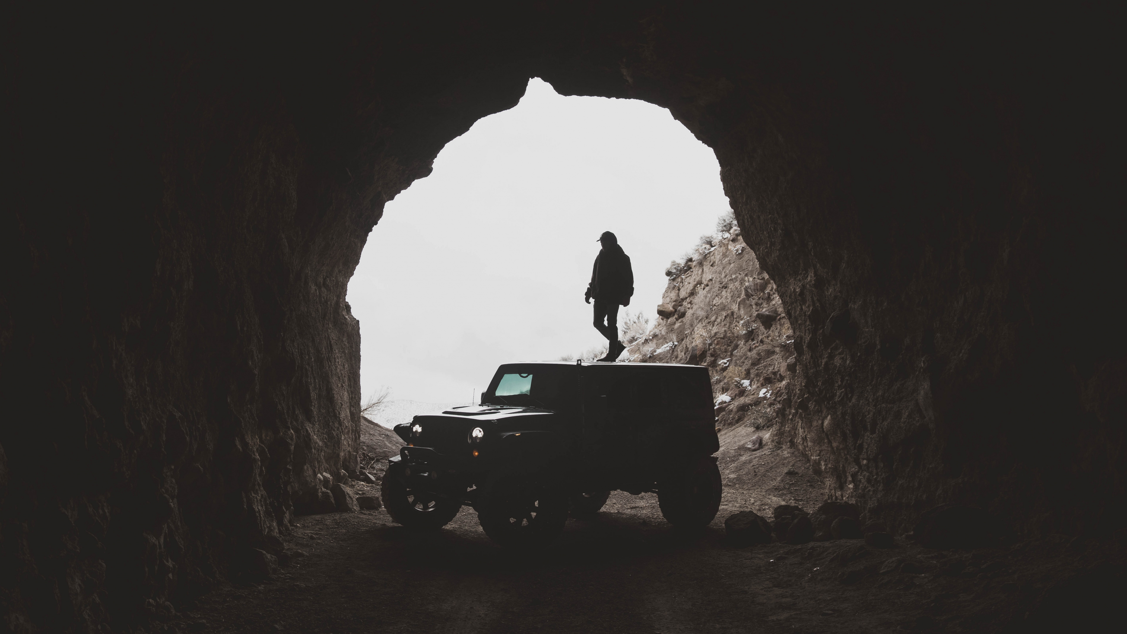 Man in Black Jacket Standing on Black Jeep Wrangler Inside Cave During Daytime. Wallpaper in 3840x2160 Resolution