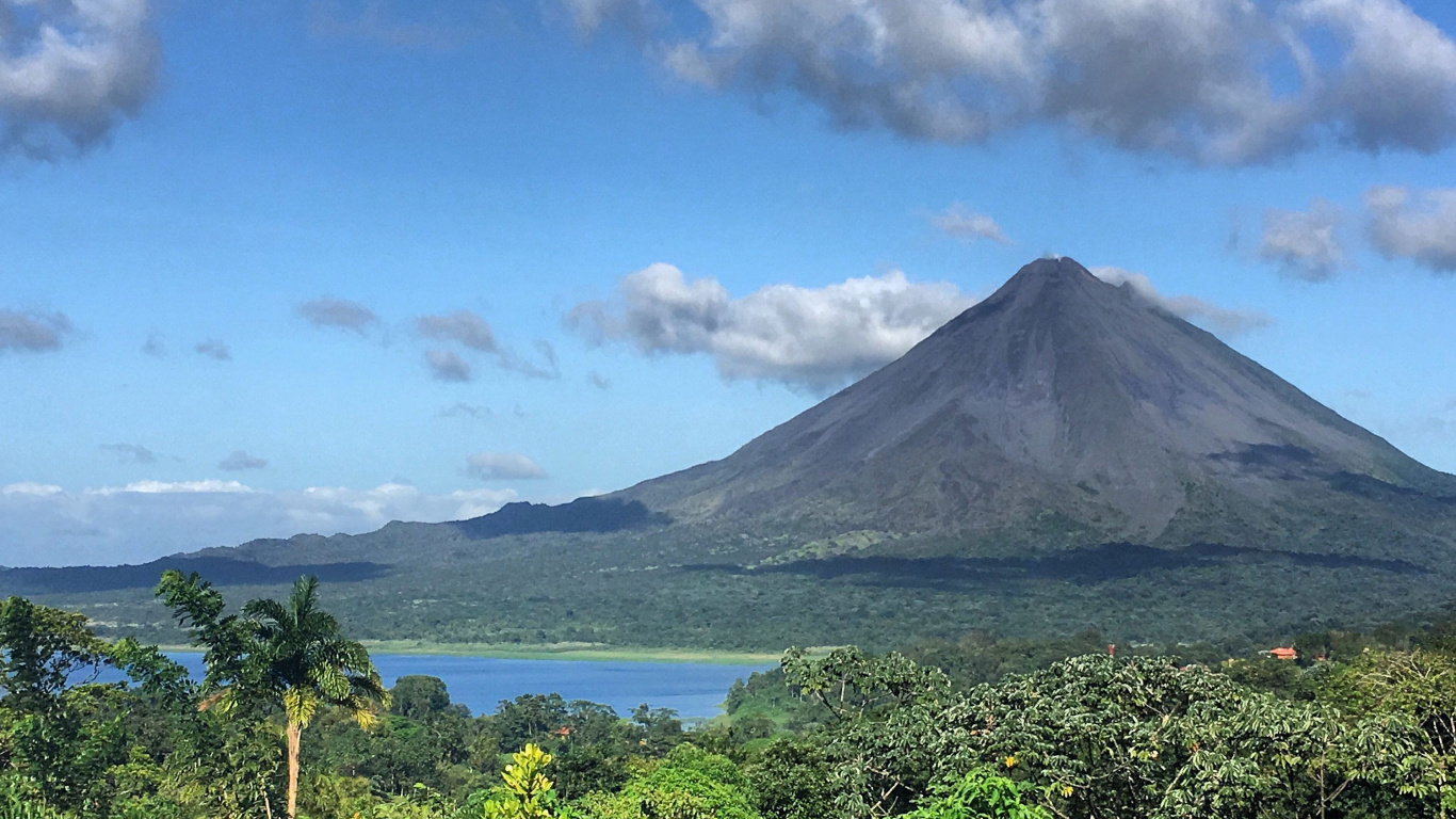 Green Mountain Near Body of Water Under Blue Sky During Daytime. Wallpaper in 1366x768 Resolution