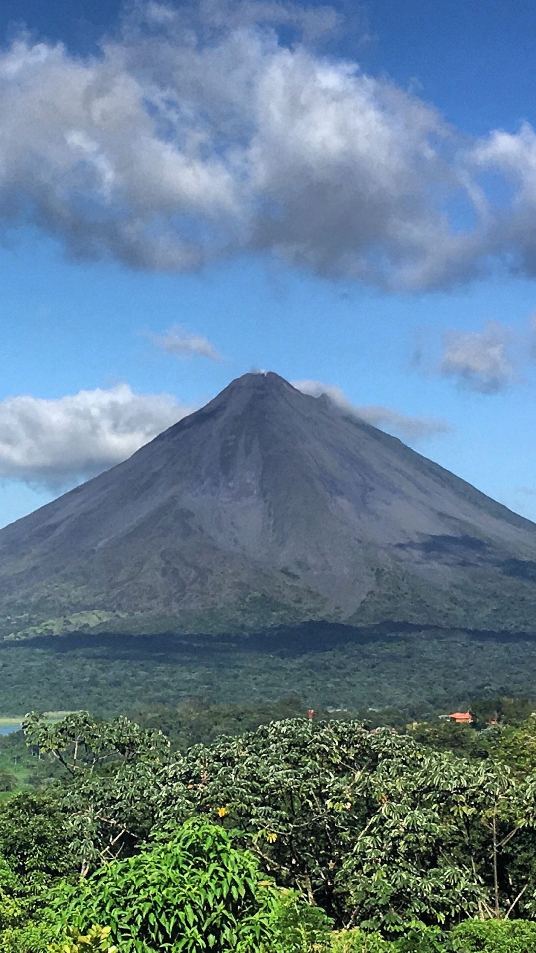 Montagne Verte Près D'un Plan D'eau Sous un Ciel Bleu Pendant la Journée. Wallpaper in 1080x1920 Resolution