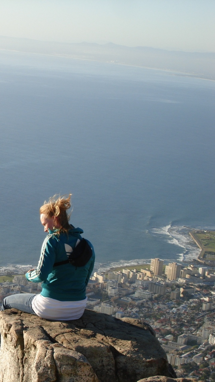 Femme en Chemise Bleue à Manches Longues Assise Sur Une Formation Rocheuse Près de la Mer Pendant la Journée. Wallpaper in 720x1280 Resolution