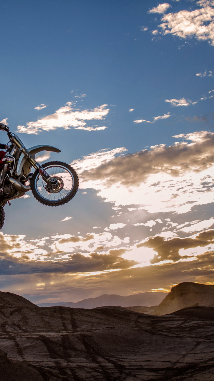 Man Riding Motocross Dirt Bike Sur Brown Mountain Sous Ciel Bleu Pendant la Journée. Wallpaper in 750x1334 Resolution