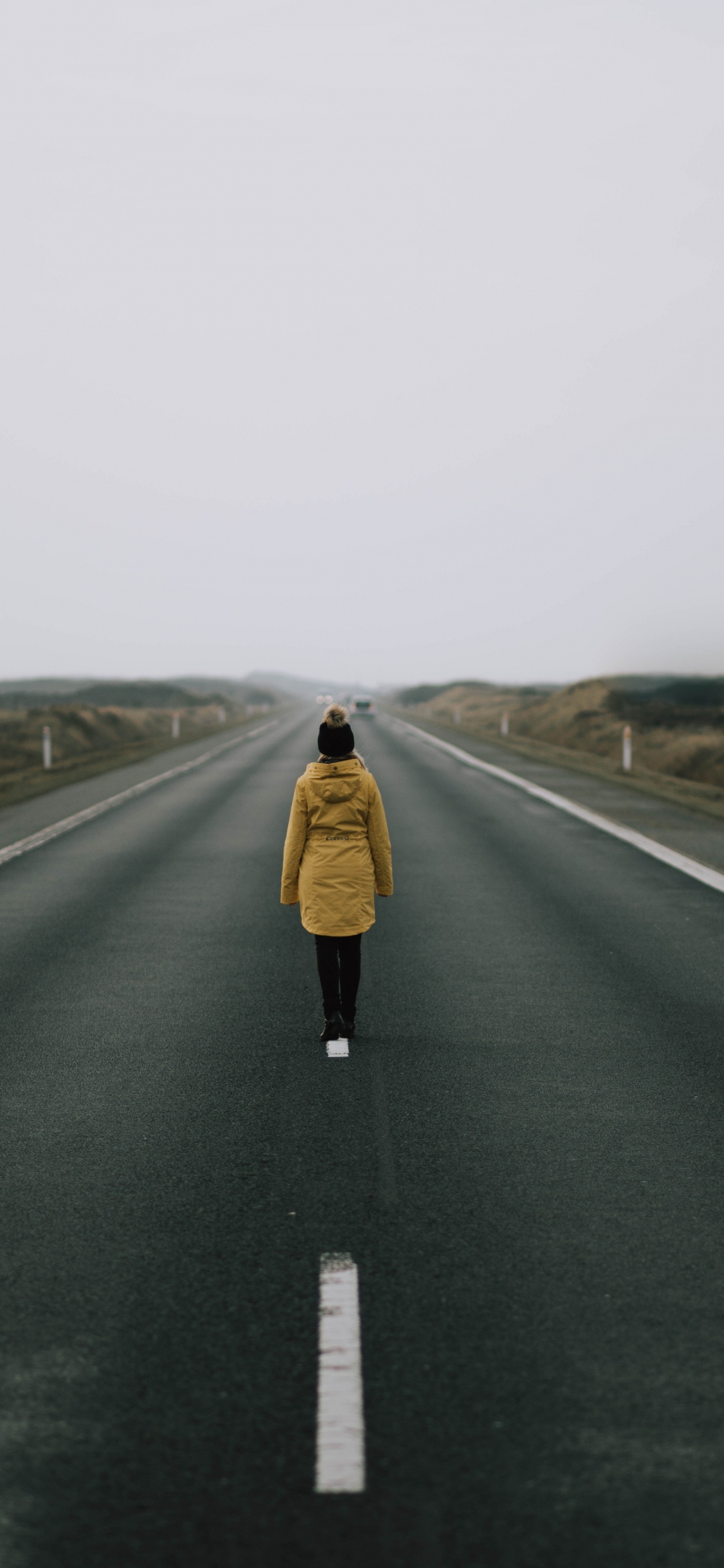 Woman in Brown Coat Standing on Road During Daytime. Wallpaper in 1125x2436 Resolution