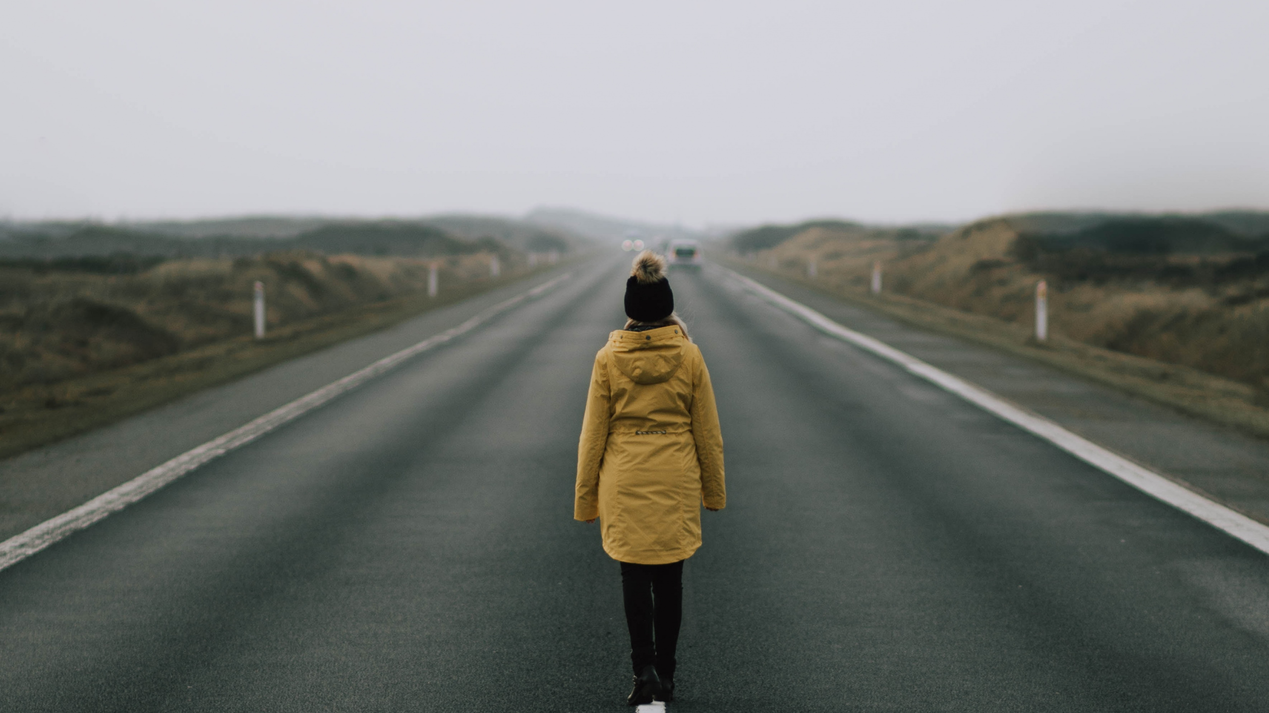 Woman in Brown Coat Standing on Road During Daytime. Wallpaper in 2560x1440 Resolution