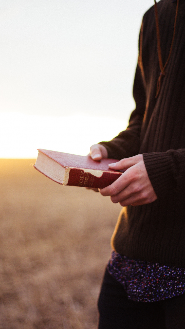 Person im Schwarzen Blazer Mit Buch. Wallpaper in 750x1334 Resolution