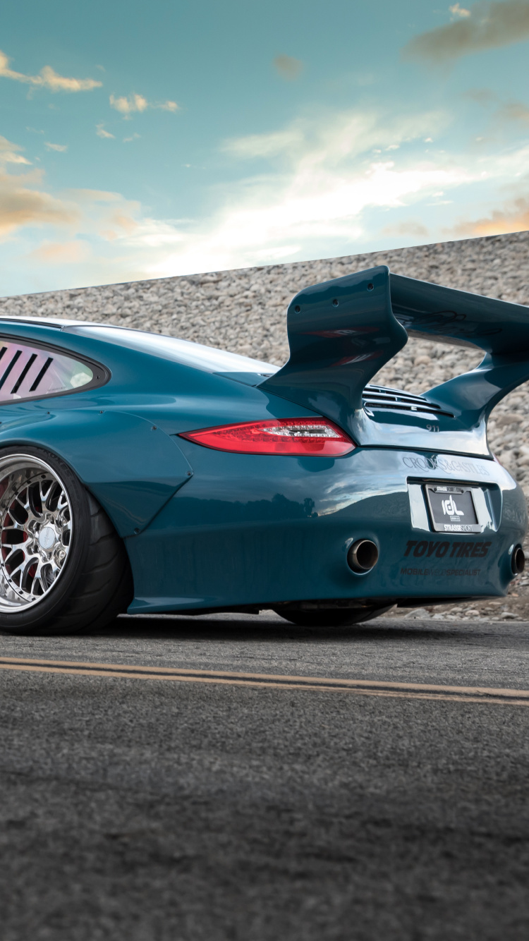 Porsche 911 Azul en la Carretera Bajo un Cielo Azul. Wallpaper in 750x1334 Resolution