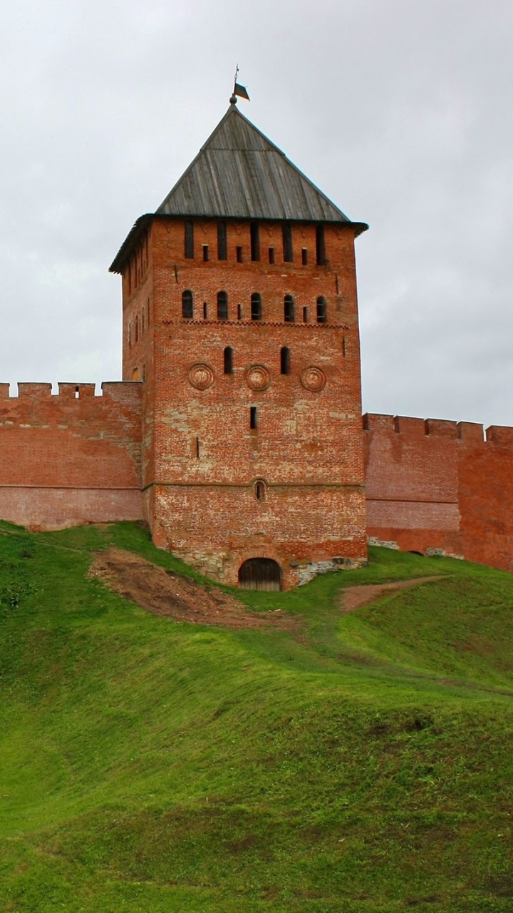 Braunes Backsteingebäude Auf Grüner Wiese Unter Weißen Wolken Tagsüber. Wallpaper in 720x1280 Resolution