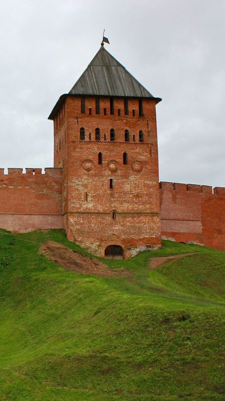 Braunes Backsteingebäude Auf Grüner Wiese Unter Weißen Wolken Tagsüber. Wallpaper in 750x1334 Resolution