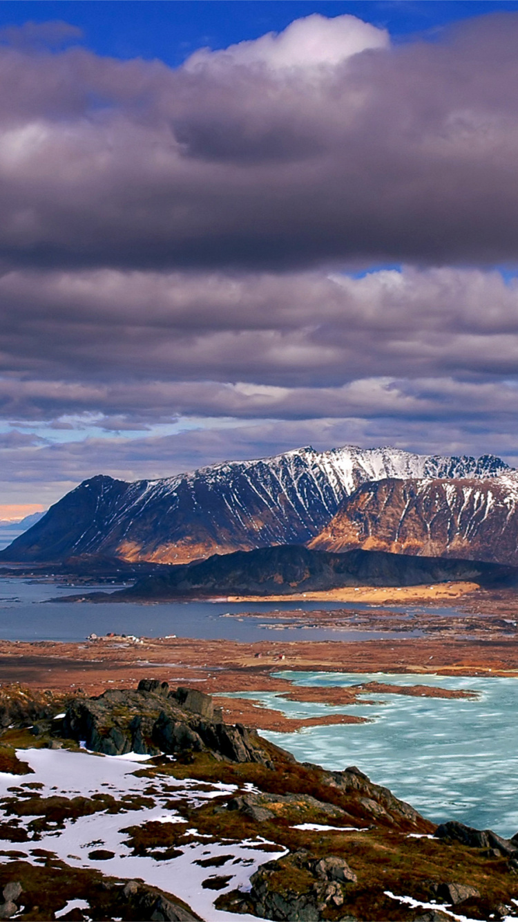 Brown and White Mountains Near Body of Water Under Cloudy Sky During Daytime. Wallpaper in 750x1334 Resolution