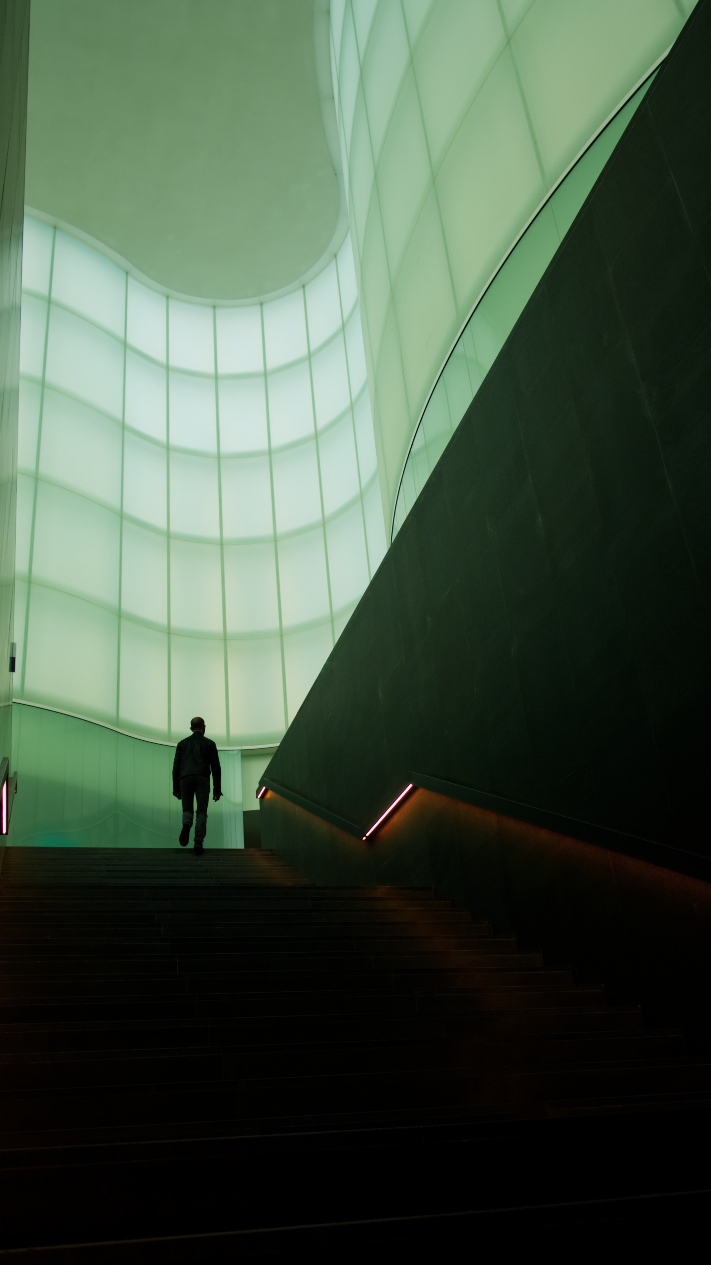 Man in Black Jacket Walking on Brown Staircase. Wallpaper in 1440x2560 Resolution