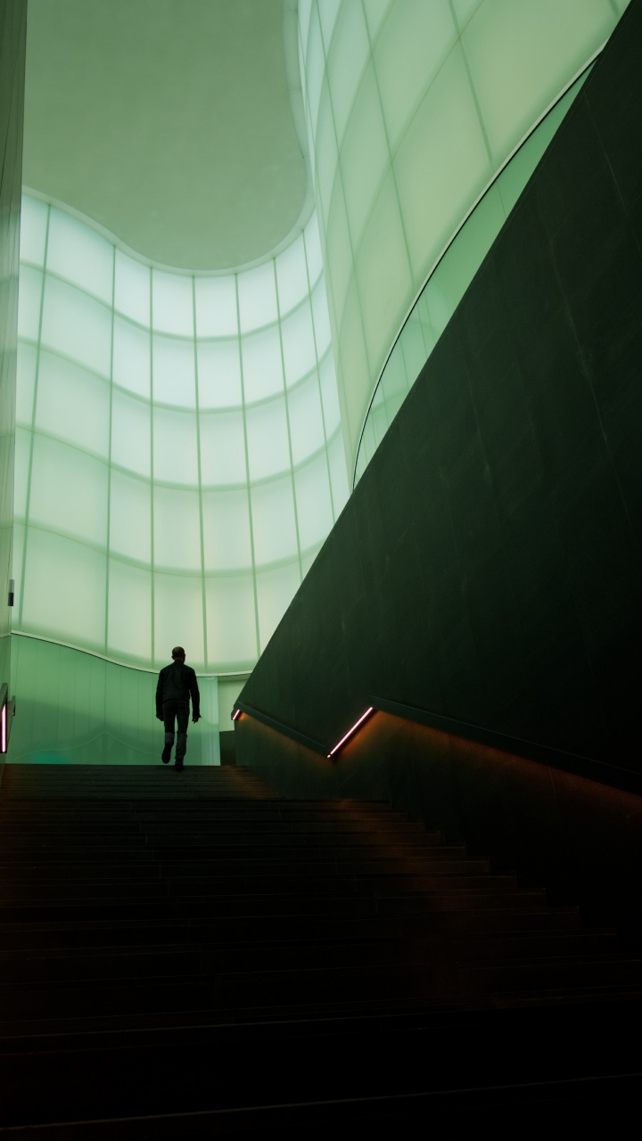 Man in Black Jacket Walking on Brown Staircase. Wallpaper in 720x1280 Resolution