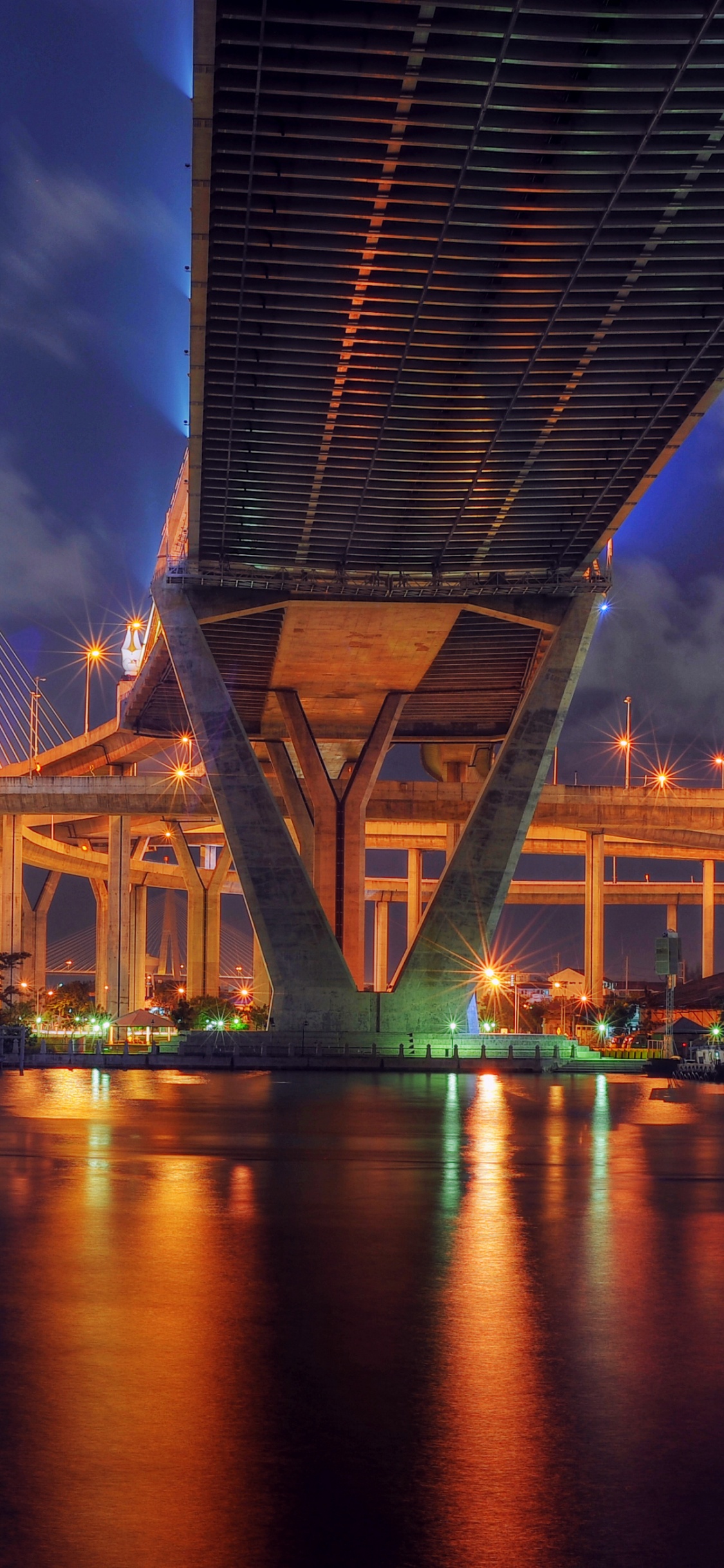 Brown Bridge Over Body of Water During Night Time. Wallpaper in 1125x2436 Resolution