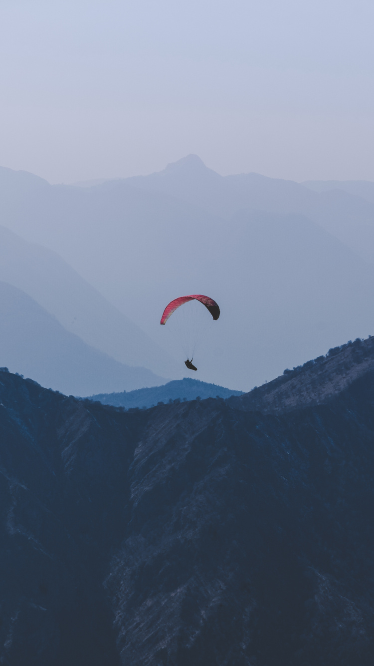 Persona en Paracaídas Naranja Sobre Montañas Verdes Durante el Día. Wallpaper in 750x1334 Resolution