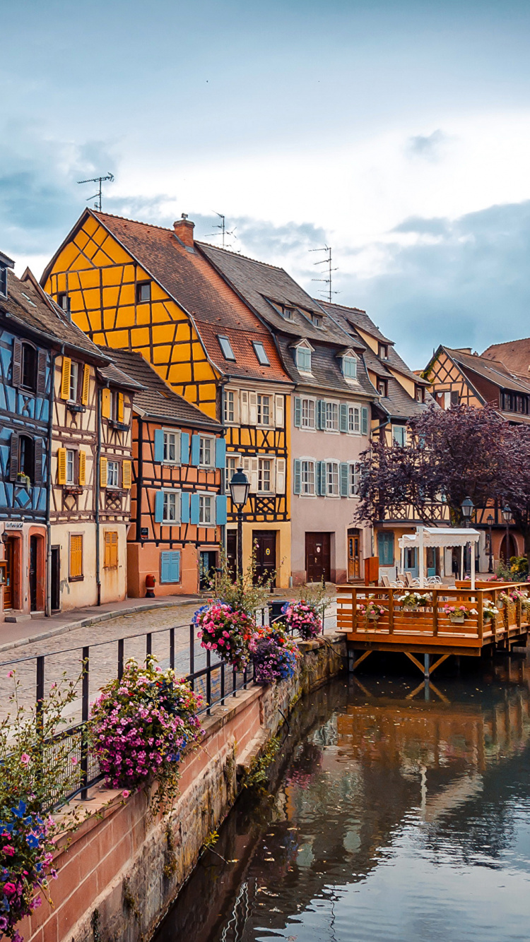 Braunes Und Weißes Betongebäude Neben Dem Fluss Unter Blauem Himmel Tagsüber. Wallpaper in 750x1334 Resolution