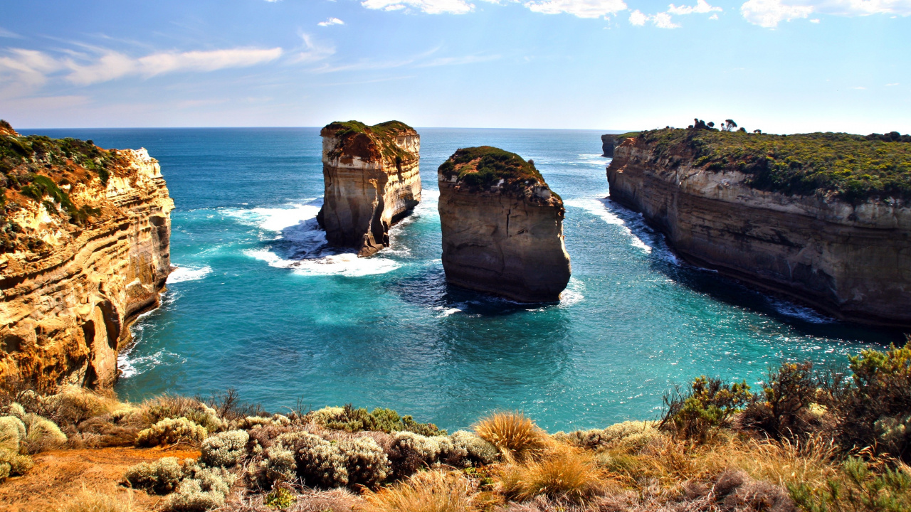 Brown and Green Rock Formation on Blue Sea Under Blue and White Cloudy Sky During Daytime. Wallpaper in 1280x720 Resolution
