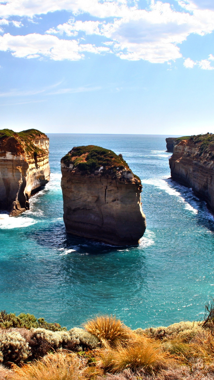 Brown and Green Rock Formation on Blue Sea Under Blue and White Cloudy Sky During Daytime. Wallpaper in 750x1334 Resolution