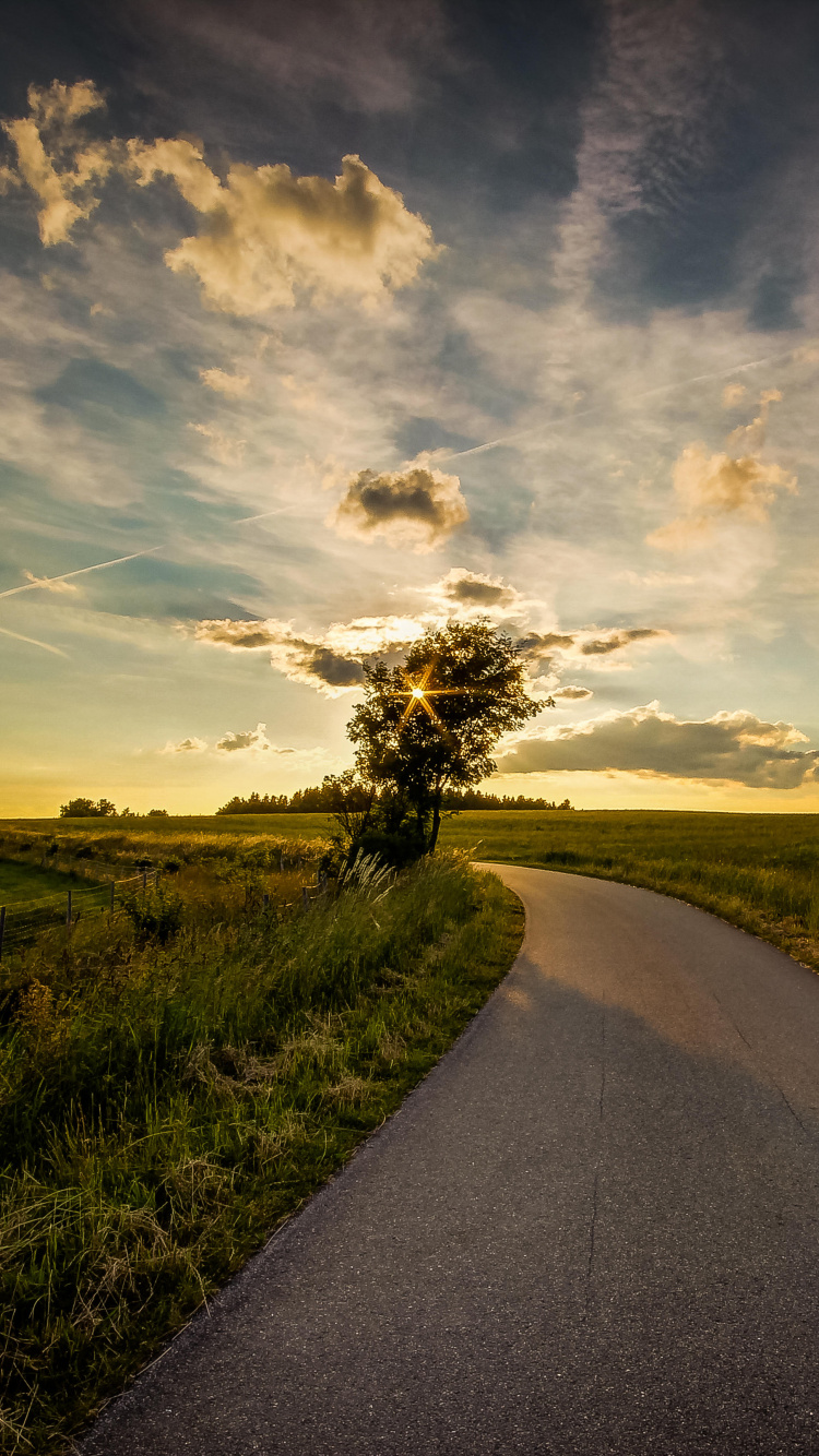 Route Asphaltée Grise Entre Champ D'herbe Verte Sous un Ciel Nuageux Ensoleillé Bleu et Blanc Pendant la Journée. Wallpaper in 750x1334 Resolution