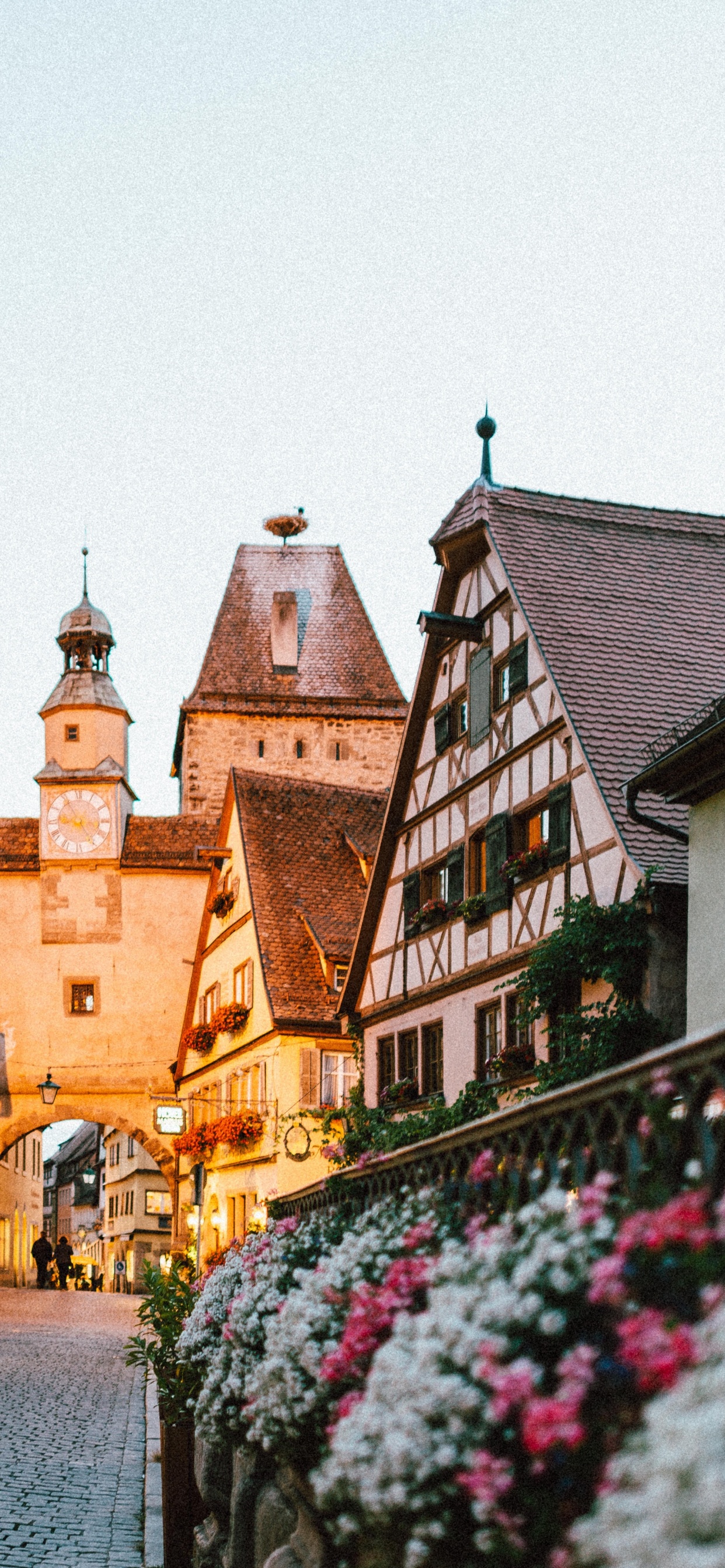 Leute, Die Tagsüber Auf Dem Bürgersteig in Der Nähe Eines Braunen Betongebäudes Gehen. Wallpaper in 1242x2688 Resolution