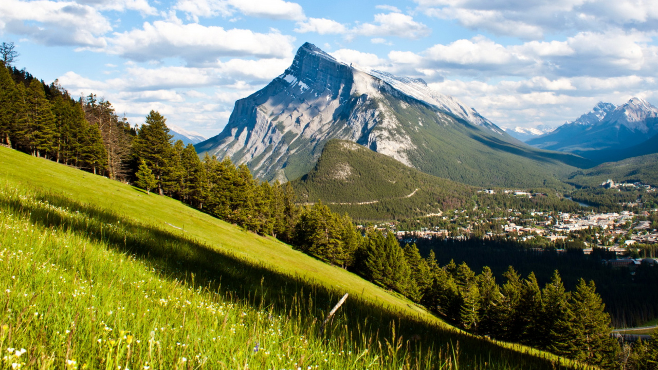 Grüne Wiese in Der Nähe Des Berges Unter Blauem Himmel Tagsüber. Wallpaper in 1280x720 Resolution