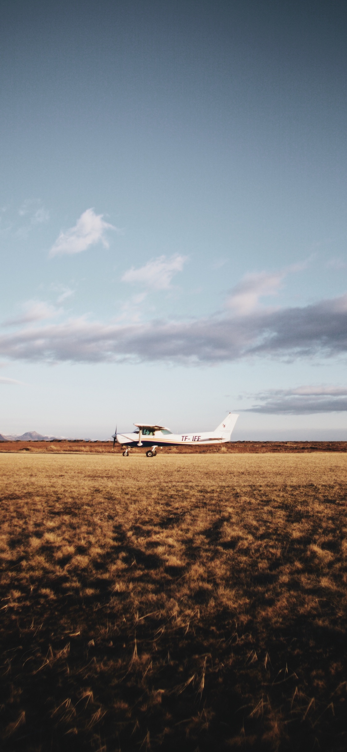 Weißes Flugzeug Auf Braunem Feld Unter Weißen Wolken Tagsüber. Wallpaper in 1125x2436 Resolution