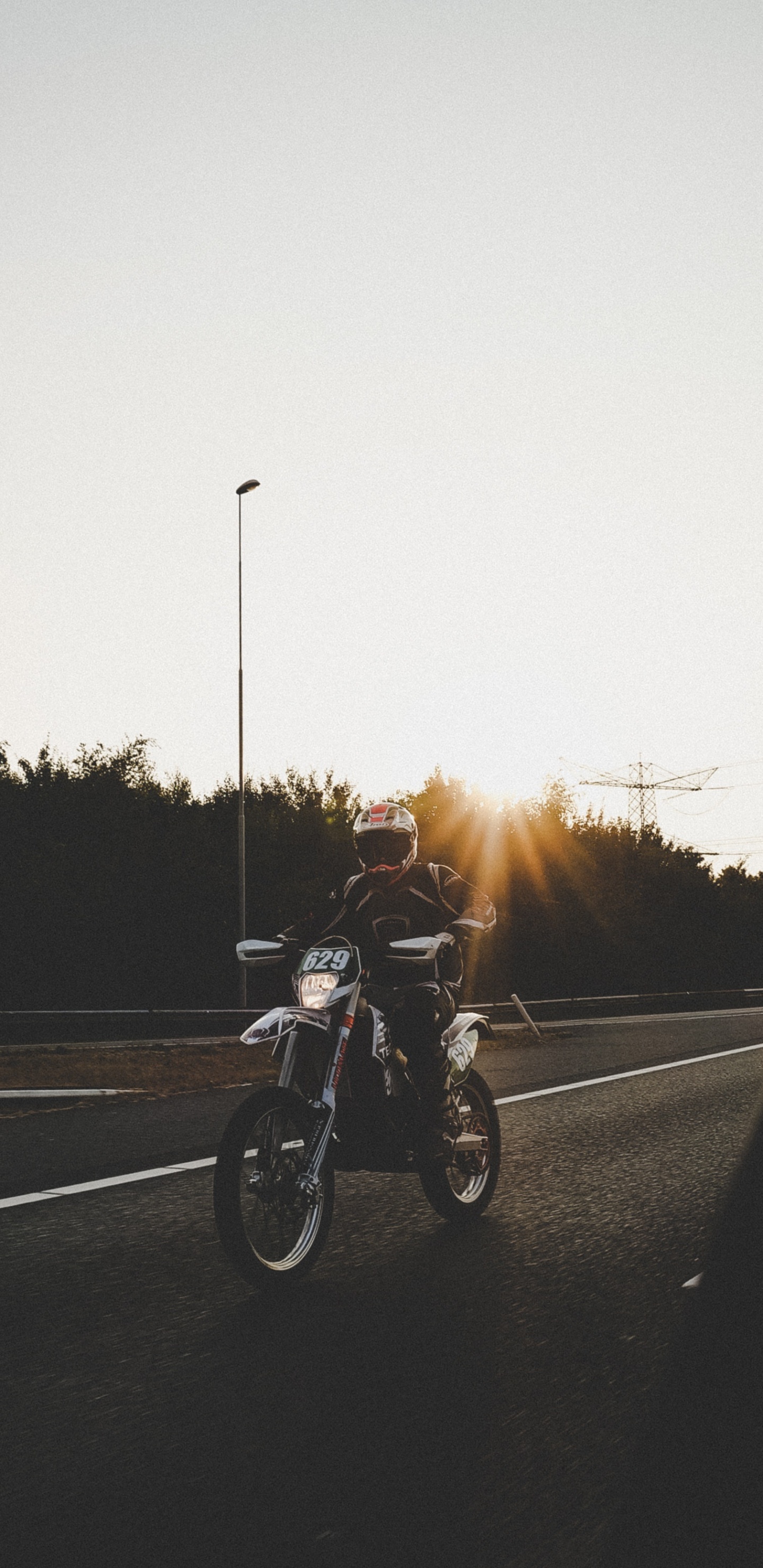 Hombre en Motocicleta en la Carretera Durante la Puesta de Sol. Wallpaper in 1440x2960 Resolution
