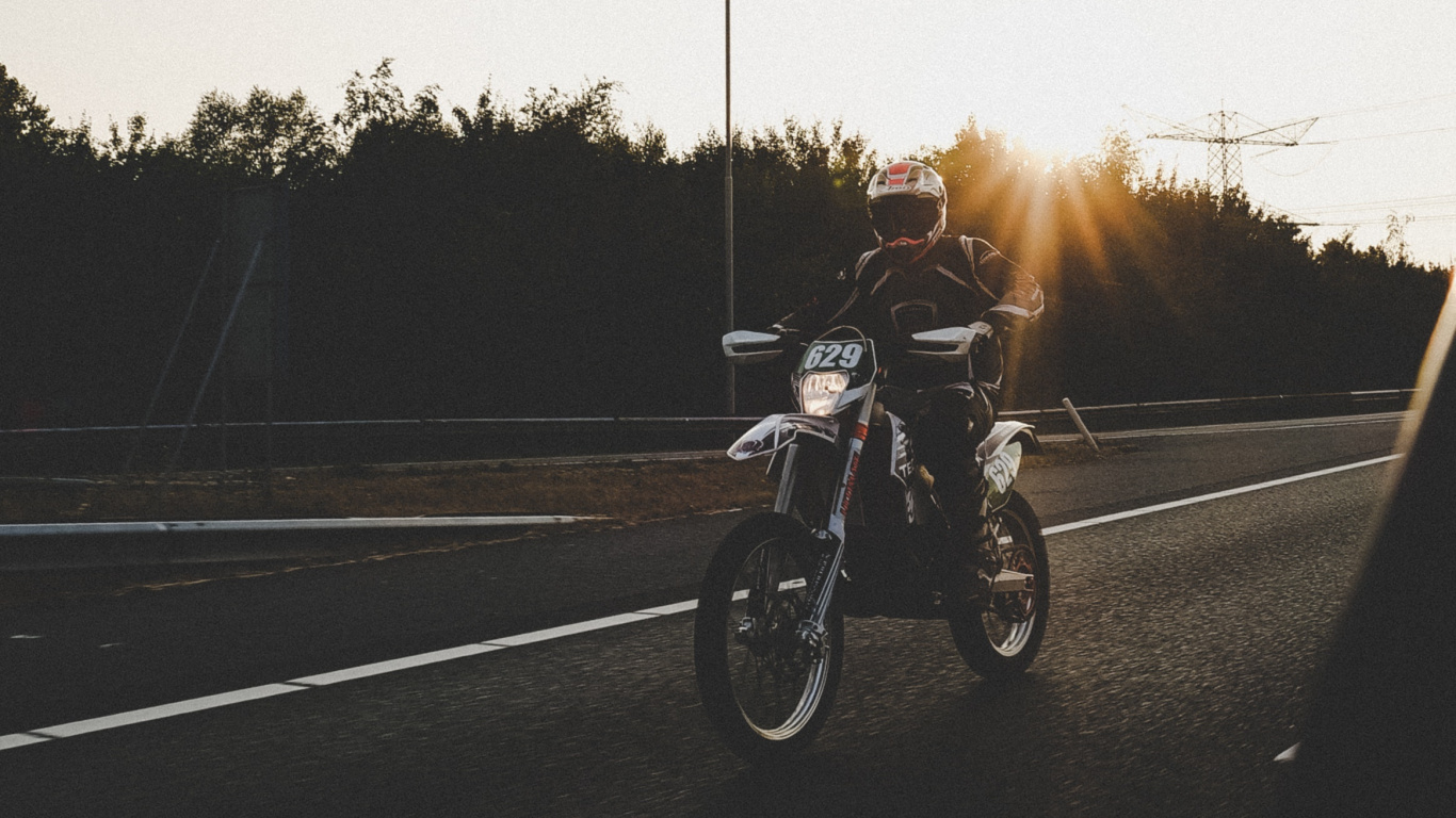 Man Riding Motorcycle Sur Route Pendant le Coucher du Soleil. Wallpaper in 1366x768 Resolution