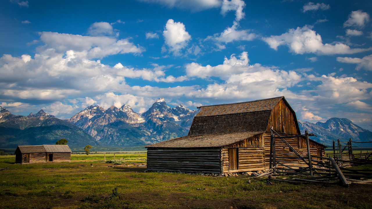 Brown Wooden Barn on Green Grass Field Near Snow Covered Mountains Under Blue and White Cloudy. Wallpaper in 1280x720 Resolution