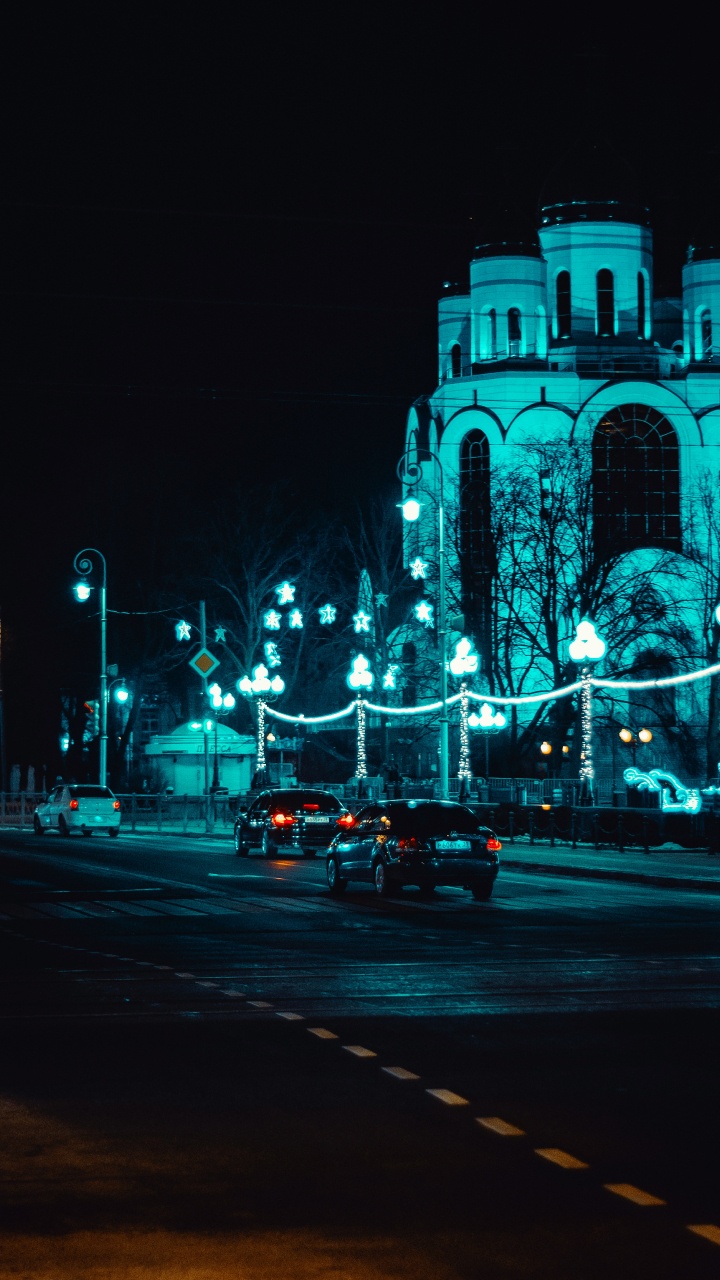 Voitures Sur Route Près D'un Bâtiment Éclairé Pendant la Nuit. Wallpaper in 720x1280 Resolution