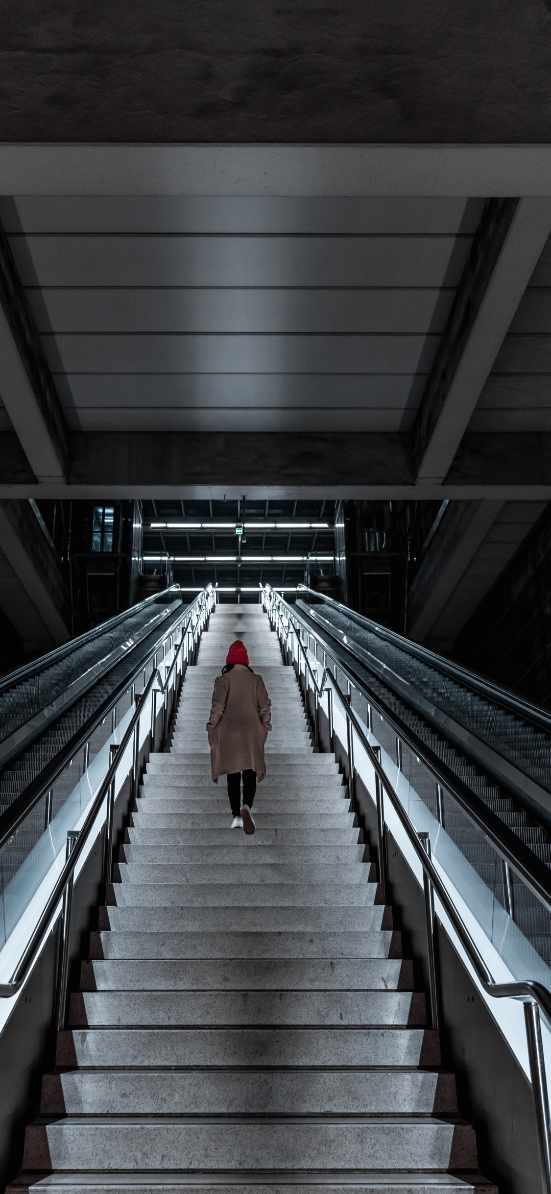 Person Walking on Gray and Black Escalator. Wallpaper in 1125x2436 Resolution