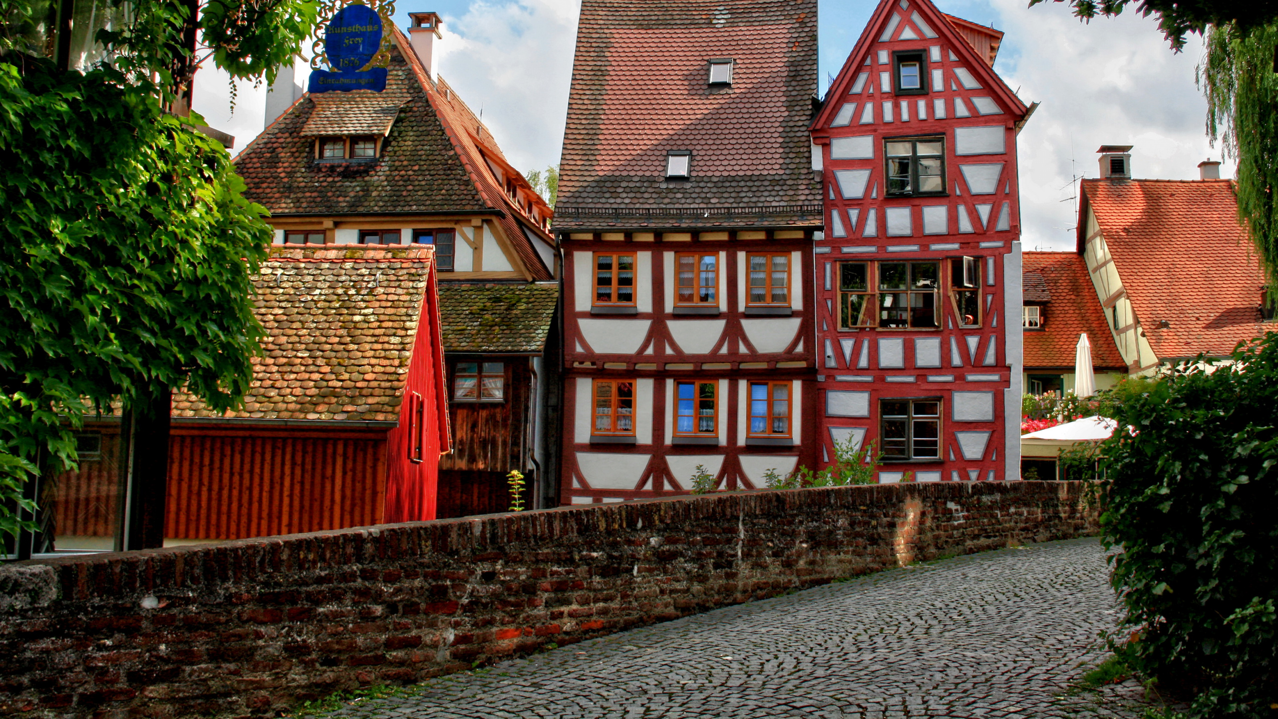 Rotes Und Braunes Betongebäude in Der Nähe Von Grünen Bäumen Tagsüber. Wallpaper in 2560x1440 Resolution