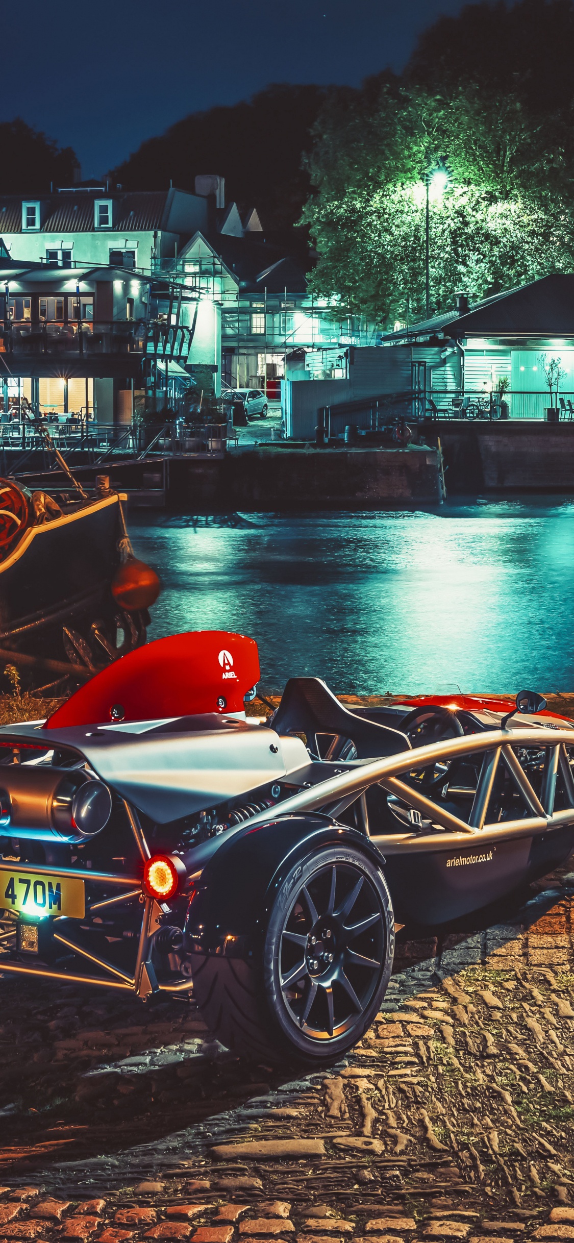 Voiture de Sport Noire et Rouge Garée à Côté D'un Plan D'eau Pendant la Nuit. Wallpaper in 1125x2436 Resolution