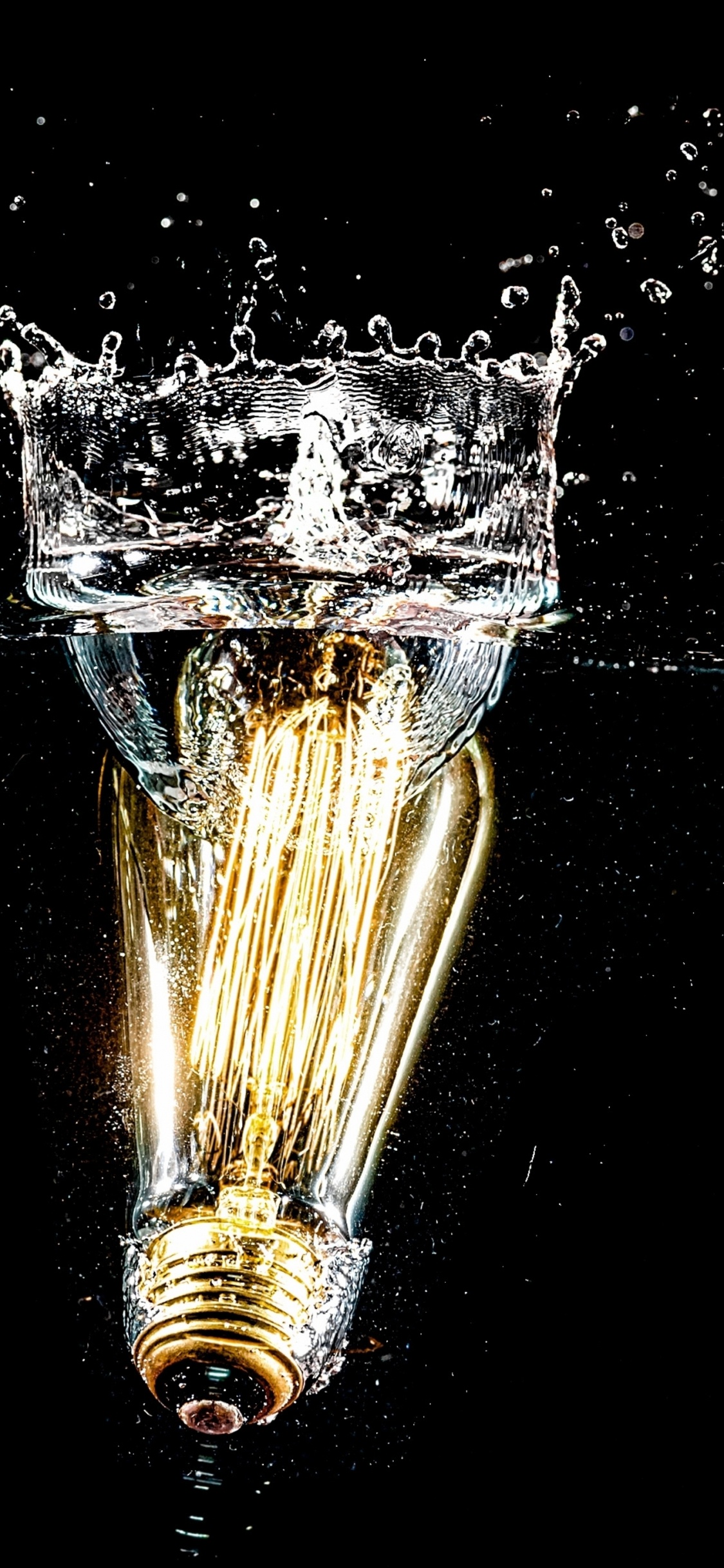 Gold Water Fountain in Black Background. Wallpaper in 1125x2436 Resolution