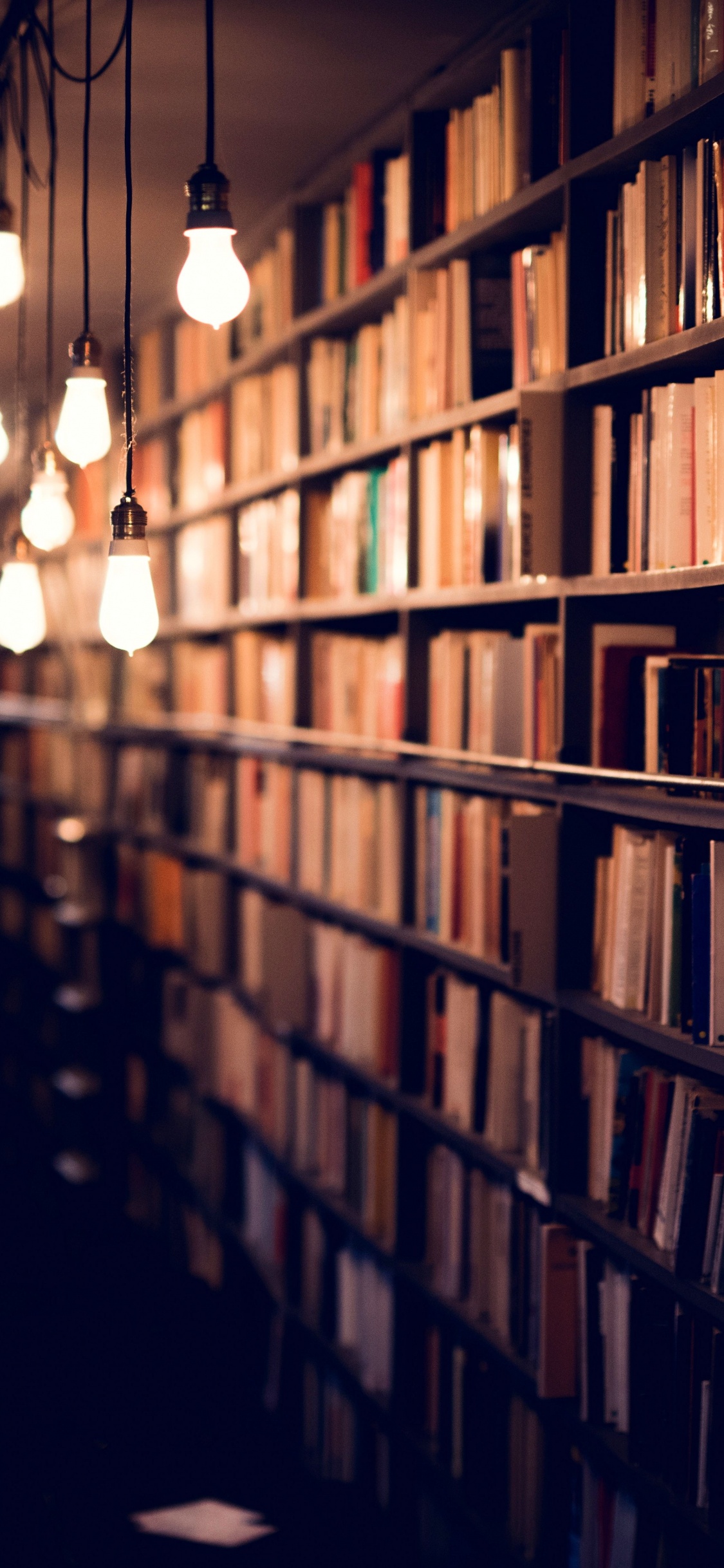 Braune Bücherregale Aus Holz Mit Licht im Zimmer. Wallpaper in 1125x2436 Resolution