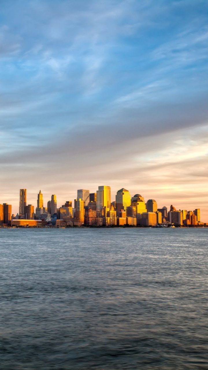 City Skyline Across Body of Water During Sunset. Wallpaper in 720x1280 Resolution