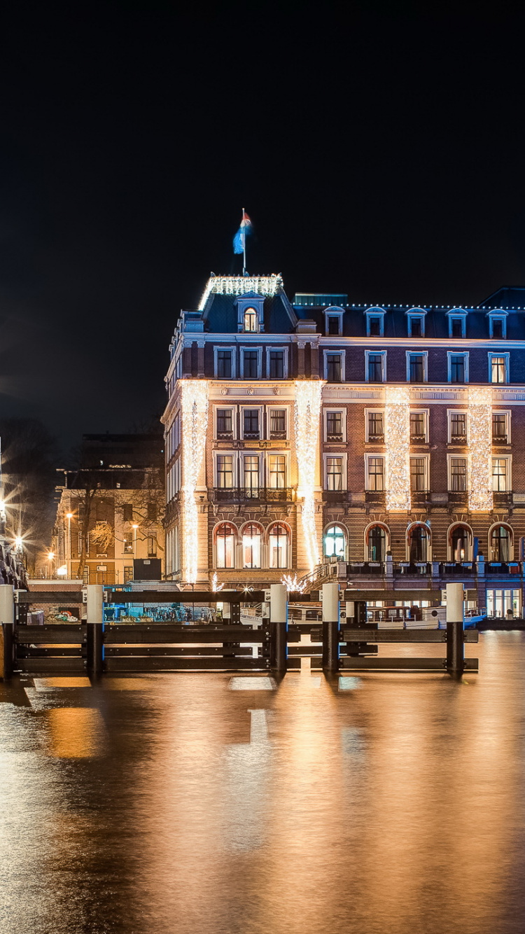 White Concrete Building Near Body of Water During Night Time. Wallpaper in 750x1334 Resolution