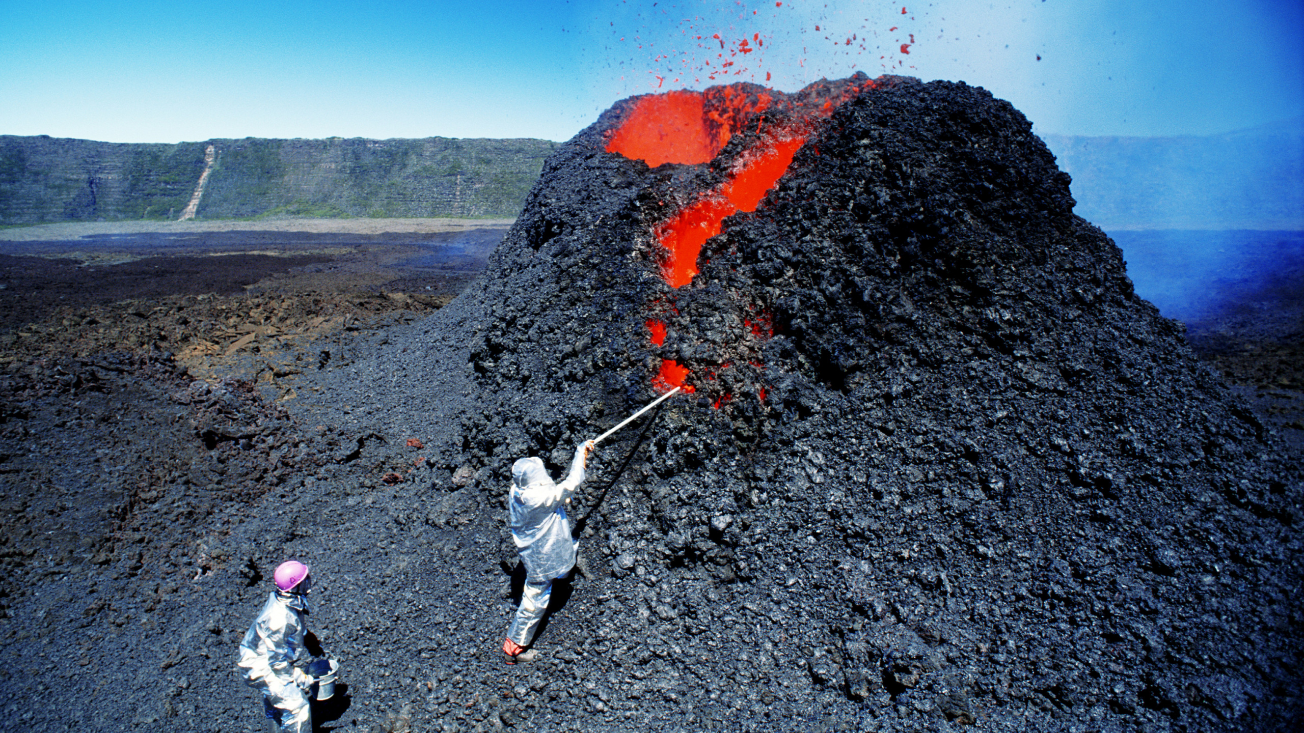 Homme en Veste Blanche et Pantalon Noir Debout Sur Une Colline Rocheuse Pendant la Journée. Wallpaper in 2560x1440 Resolution