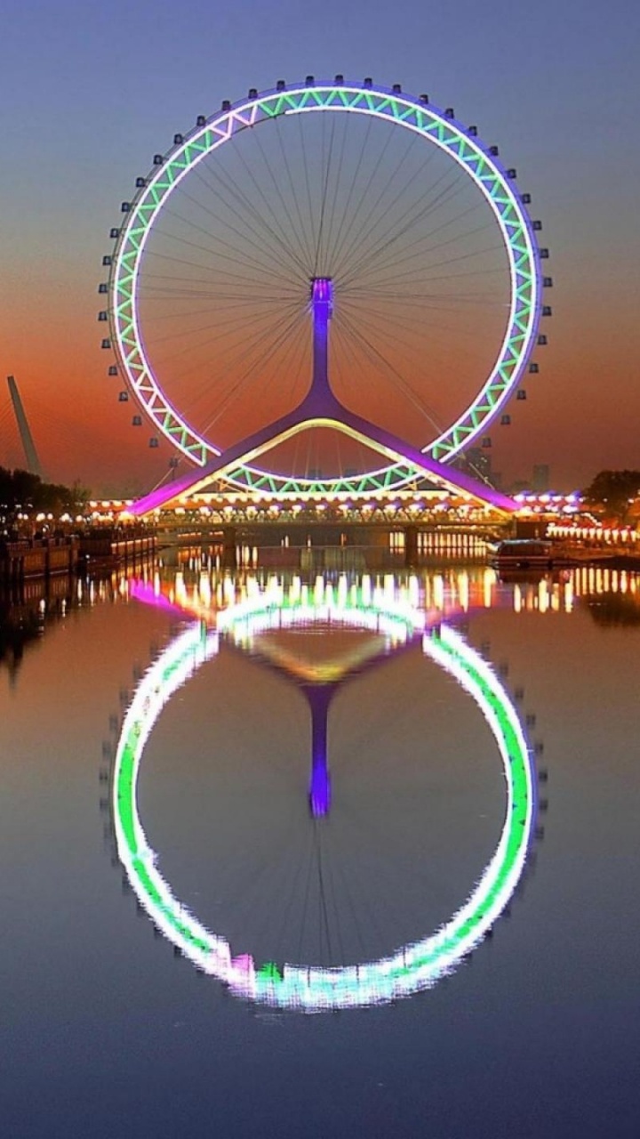 Riesenrad in Der Nähe Eines Gewässers Während Der Nacht. Wallpaper in 720x1280 Resolution