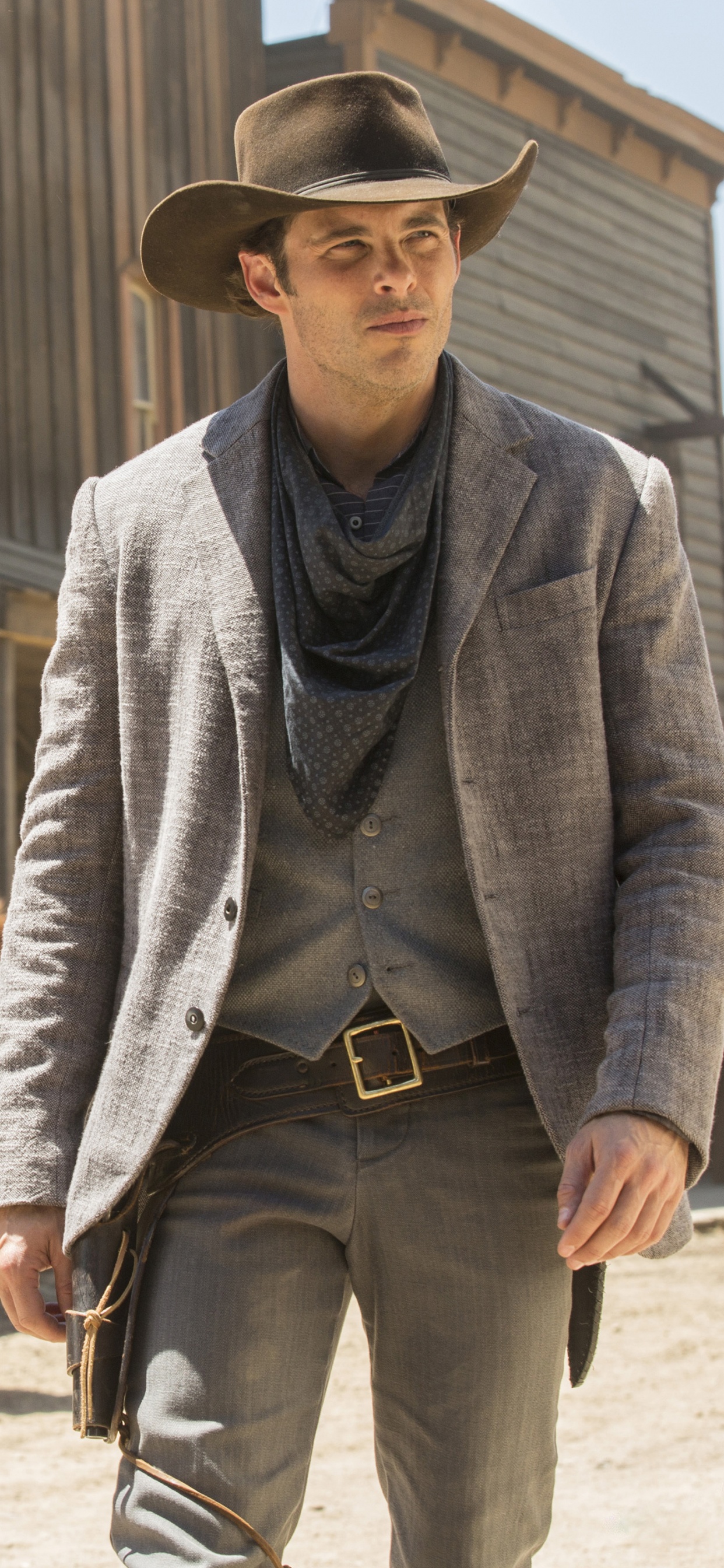 Man in Gray Blazer and Black Cowboy Hat Holding Brown Horse. Wallpaper in 1242x2688 Resolution