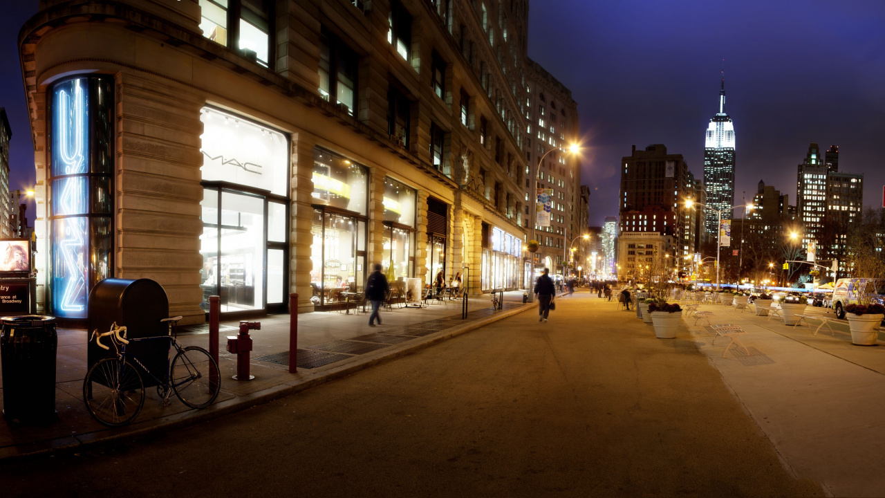 Gente Caminando en la Acera Cerca Del Edificio Durante la Noche. Wallpaper in 1280x720 Resolution