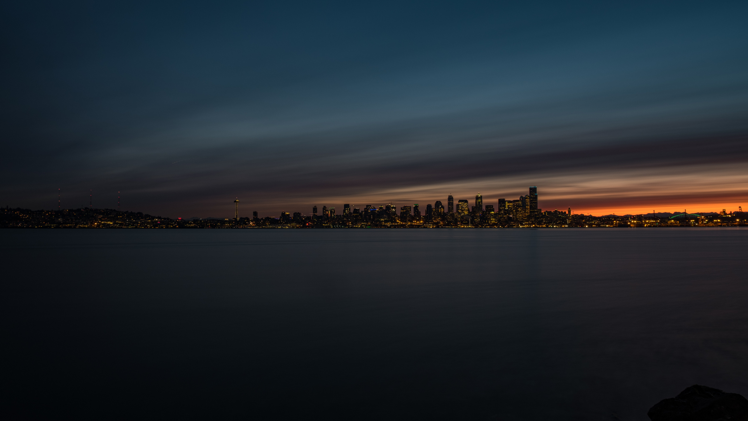 Skyline Der Stadt Über Gewässer Während Der Nacht. Wallpaper in 2560x1440 Resolution