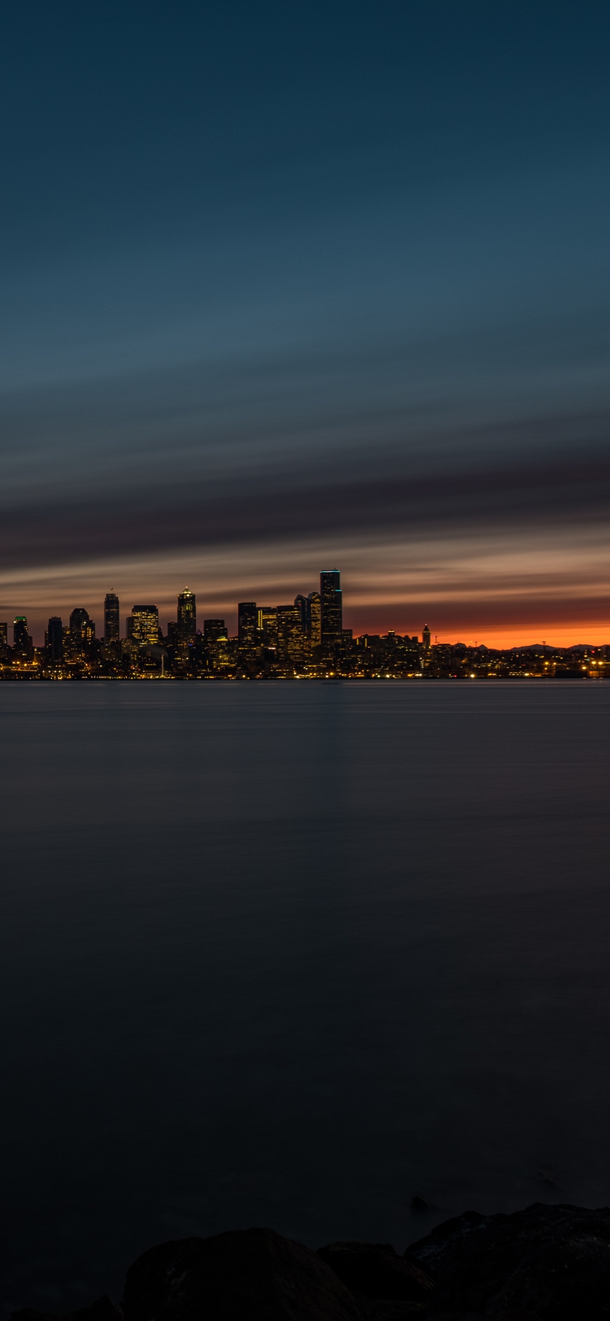 City Skyline Across Body of Water During Night Time. Wallpaper in 1242x2688 Resolution