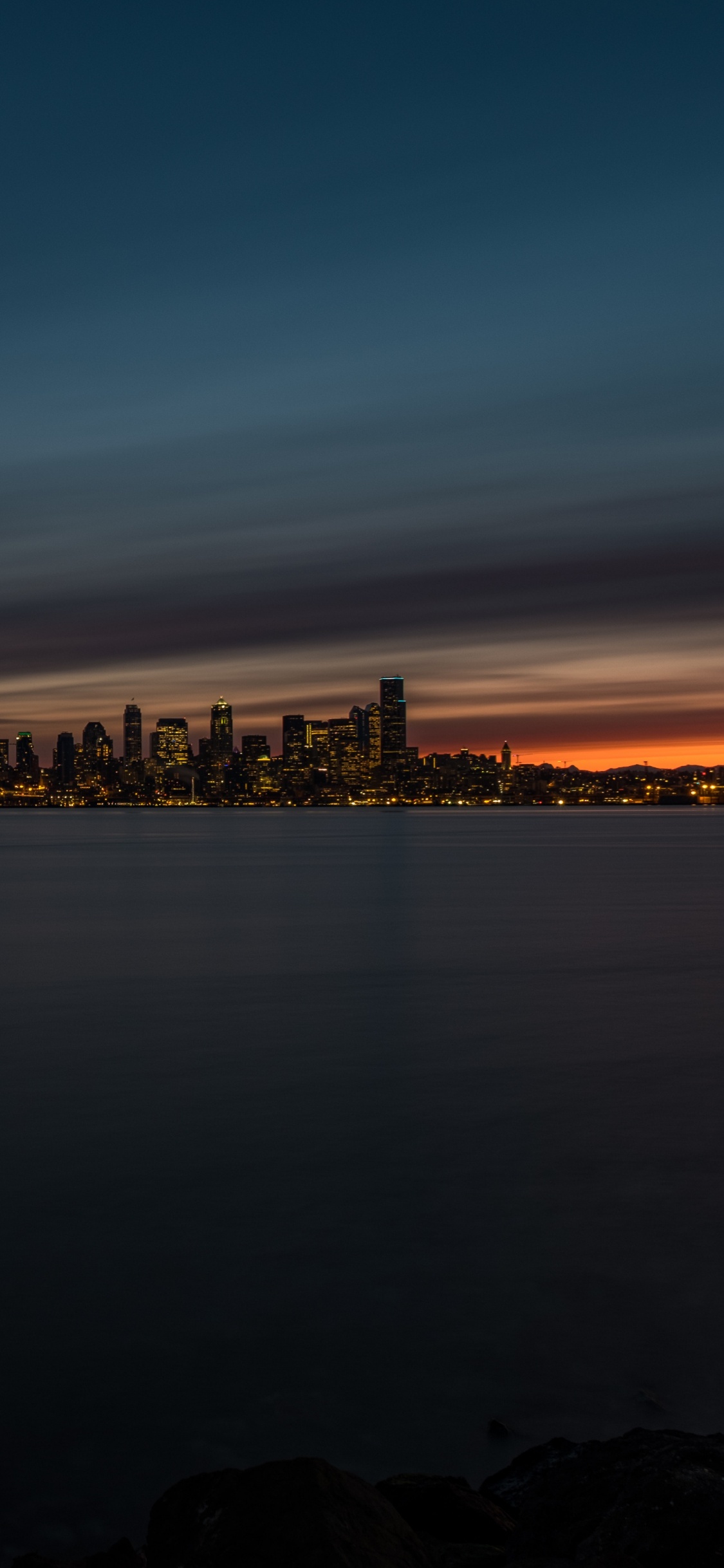 Horizon de la Ville à Travers le Plan D'eau Pendant la Nuit. Wallpaper in 1125x2436 Resolution