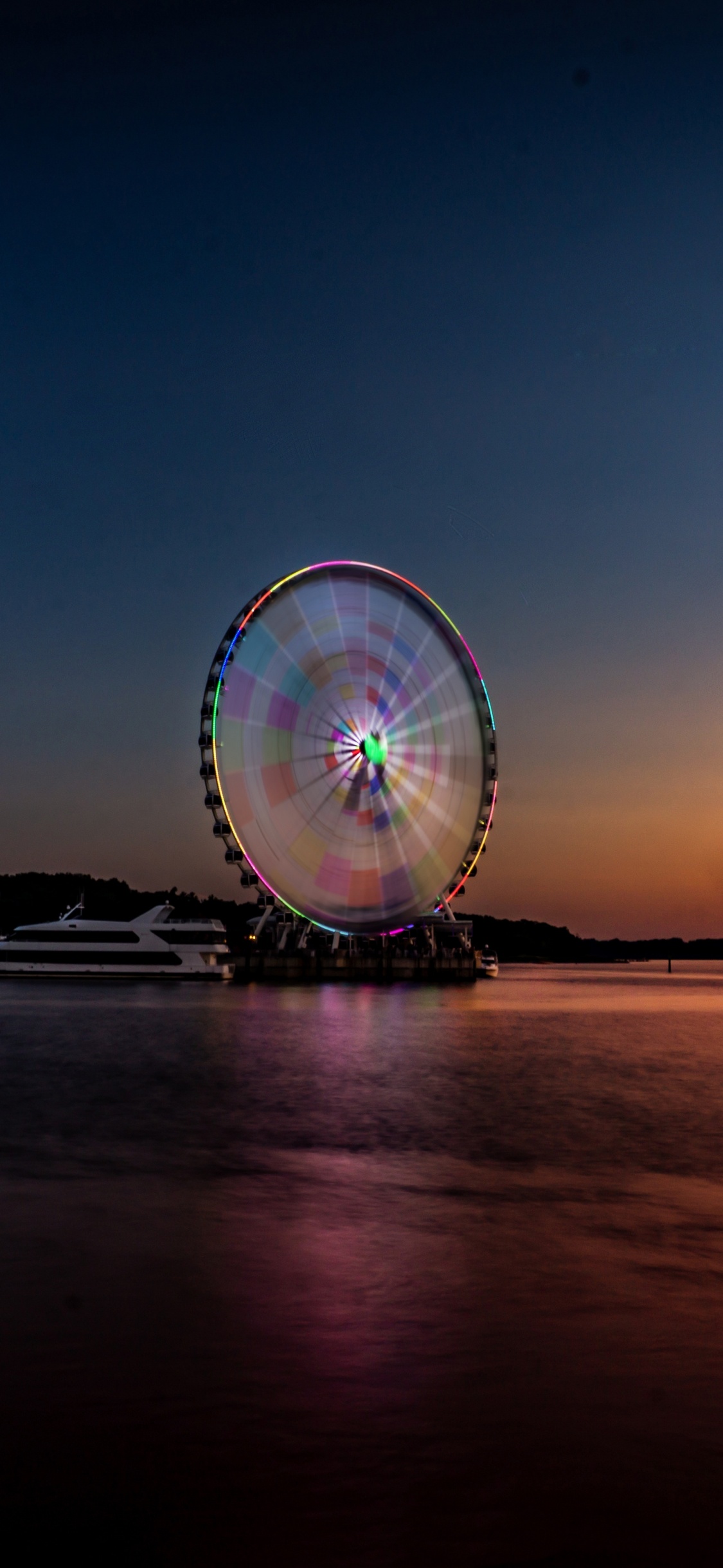Ferris Wheel Near Body of Water During Night Time. Wallpaper in 1125x2436 Resolution
