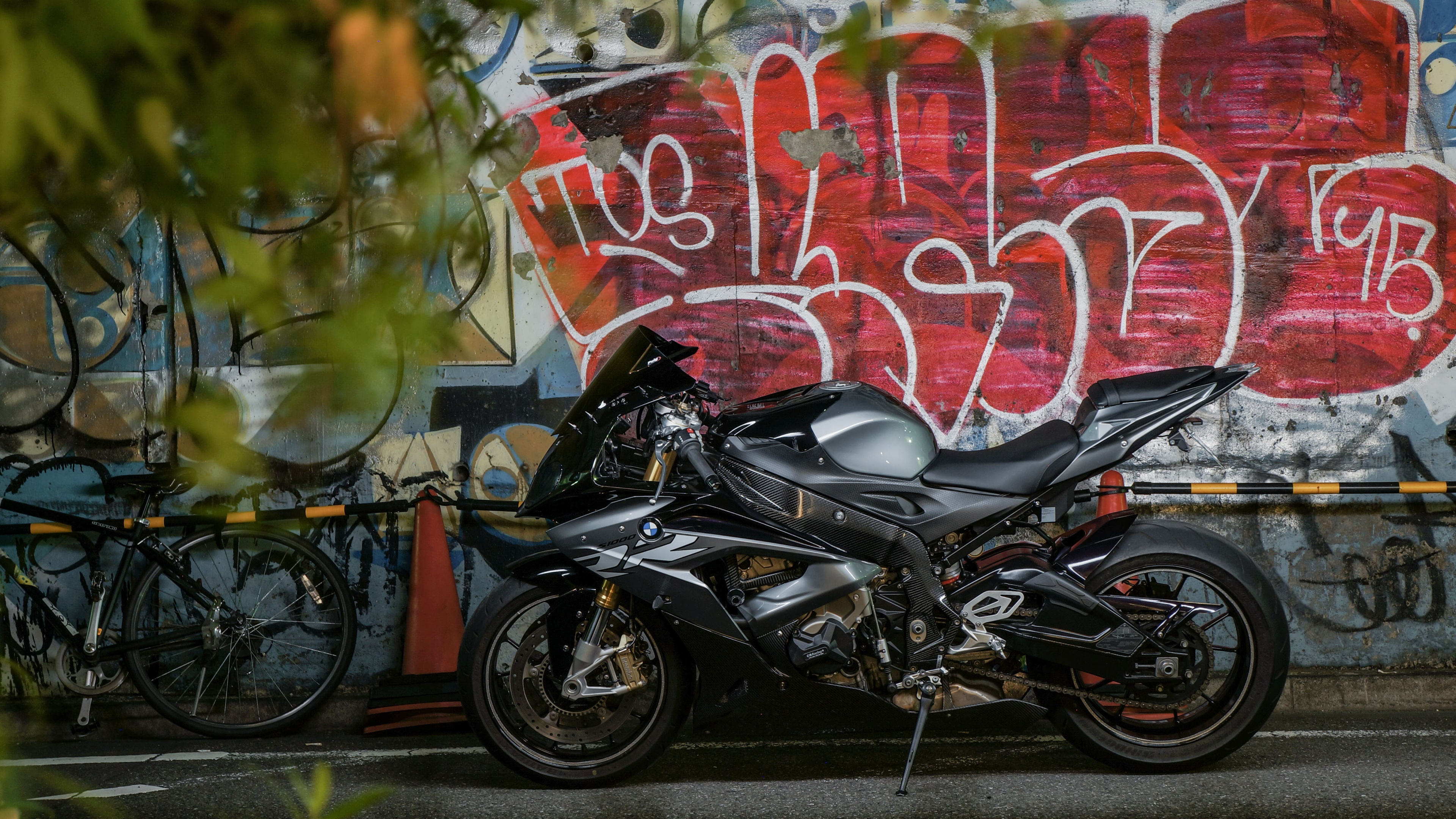 Motocicleta Negra Estacionada Junto a la Pared Con Graffiti. Wallpaper in 3840x2160 Resolution