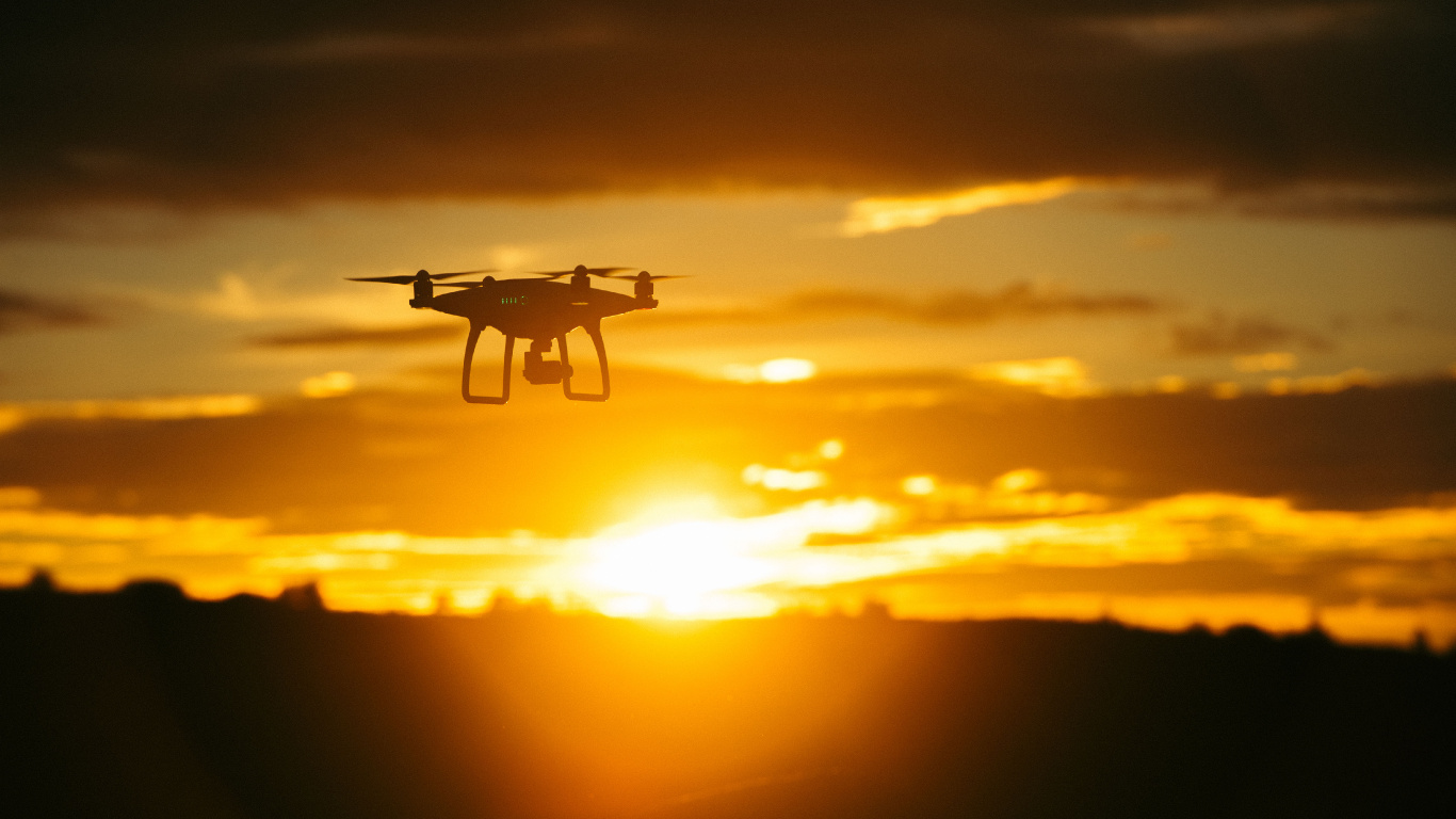 Weiße Drohne Fliegt Bei Sonnenuntergang. Wallpaper in 1366x768 Resolution