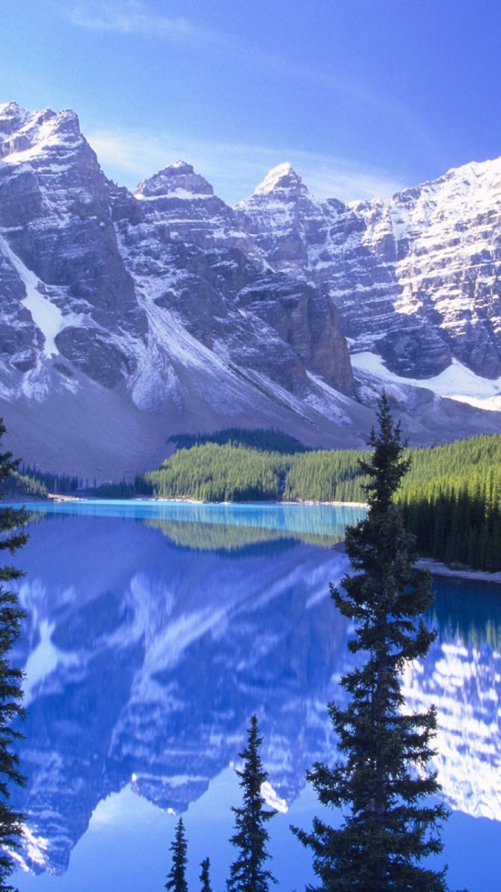 Lac Entouré D'arbres et de Montagnes Enneigées Pendant la Journée. Wallpaper in 720x1280 Resolution