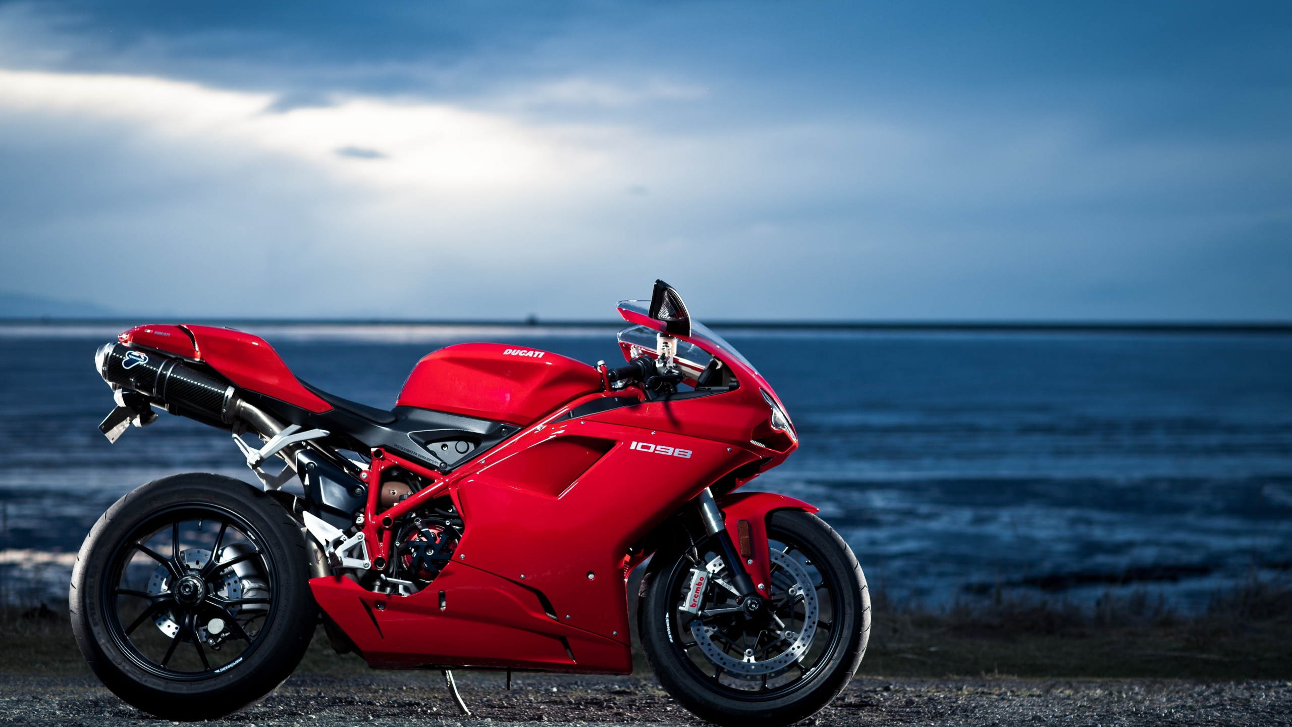 Red and Black Sports Bike Parked on Seashore During Daytime. Wallpaper in 2560x1440 Resolution